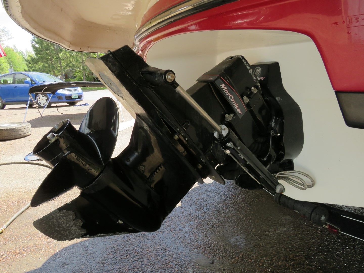 Boat's black sterndrive with propeller and trim system, mounted on the white and red hull.