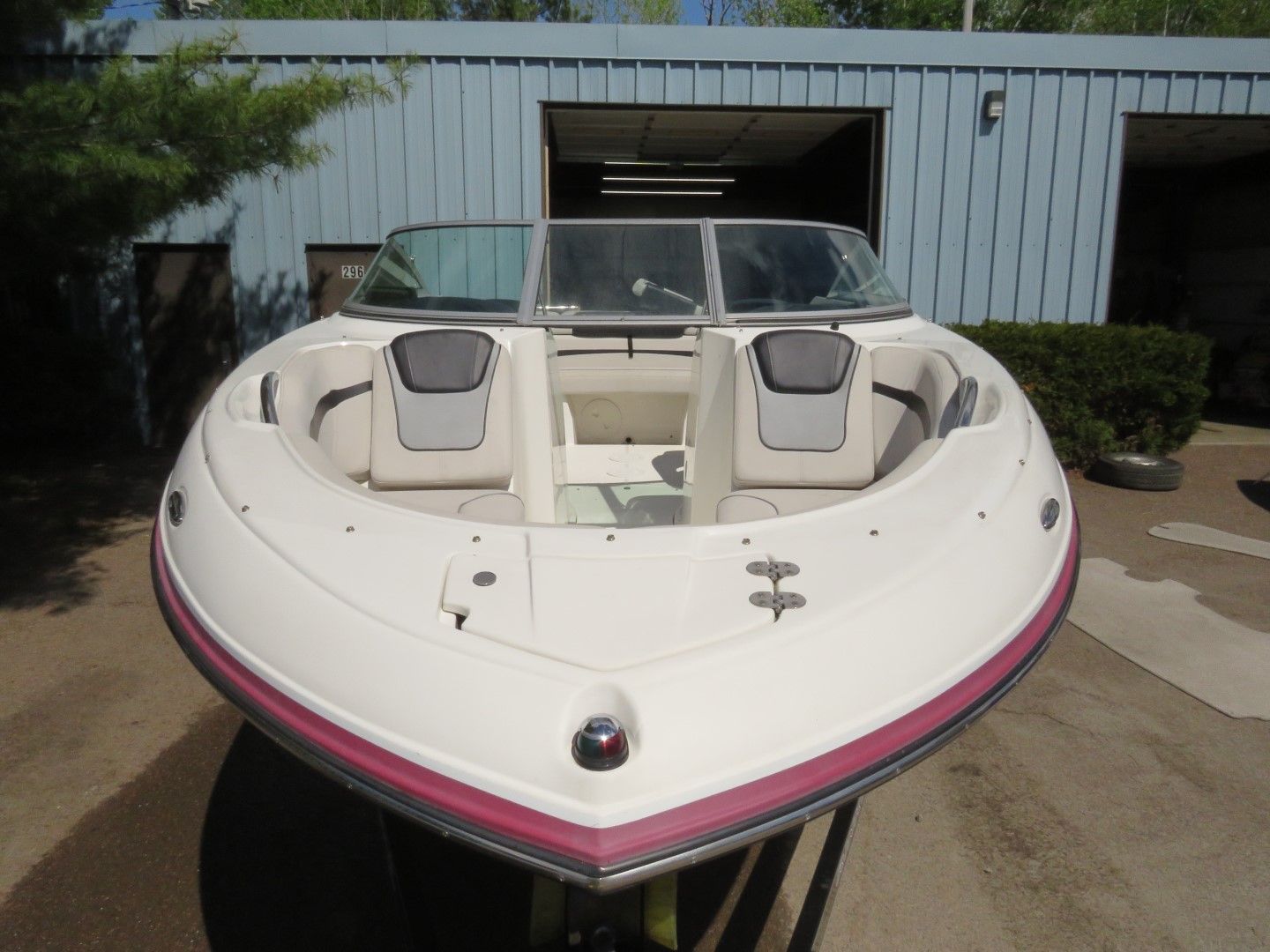 White and red speedboat in front of a blue garage, seats visible.