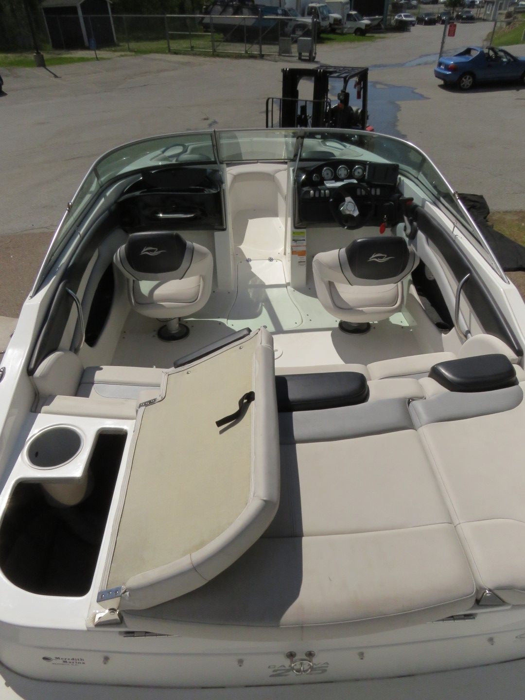 Interior of a boat with two captain's chairs, a back seat, and a side compartment.