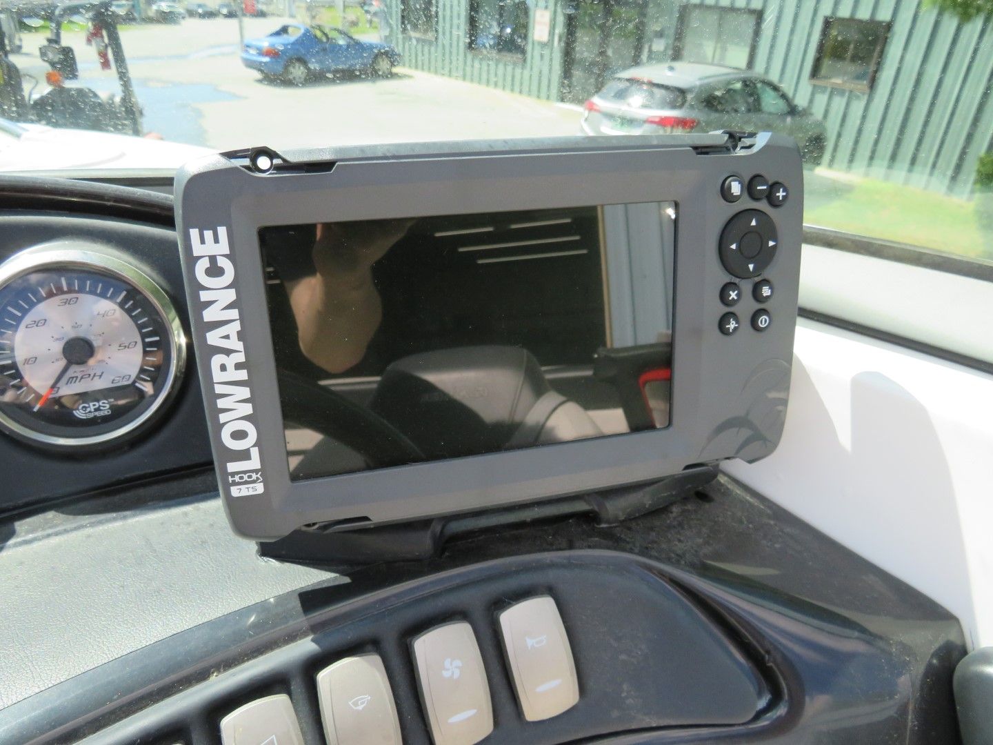 Dashboard of a boat with a Lowrance fish finder, gauge, and control buttons.