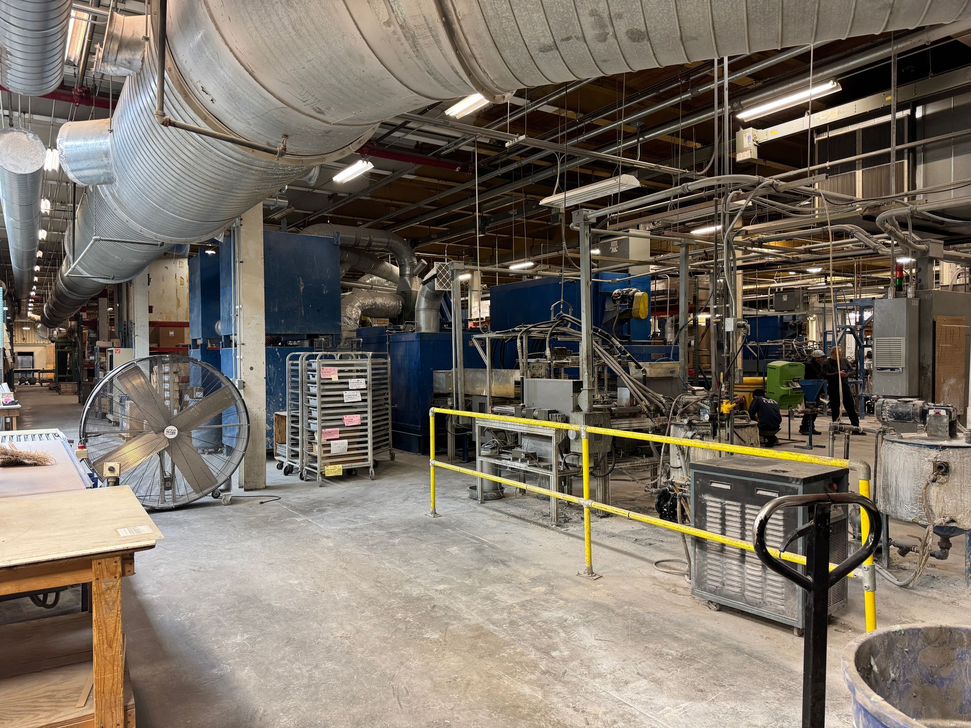 Industrial interior with machinery, ductwork, and a large fan.