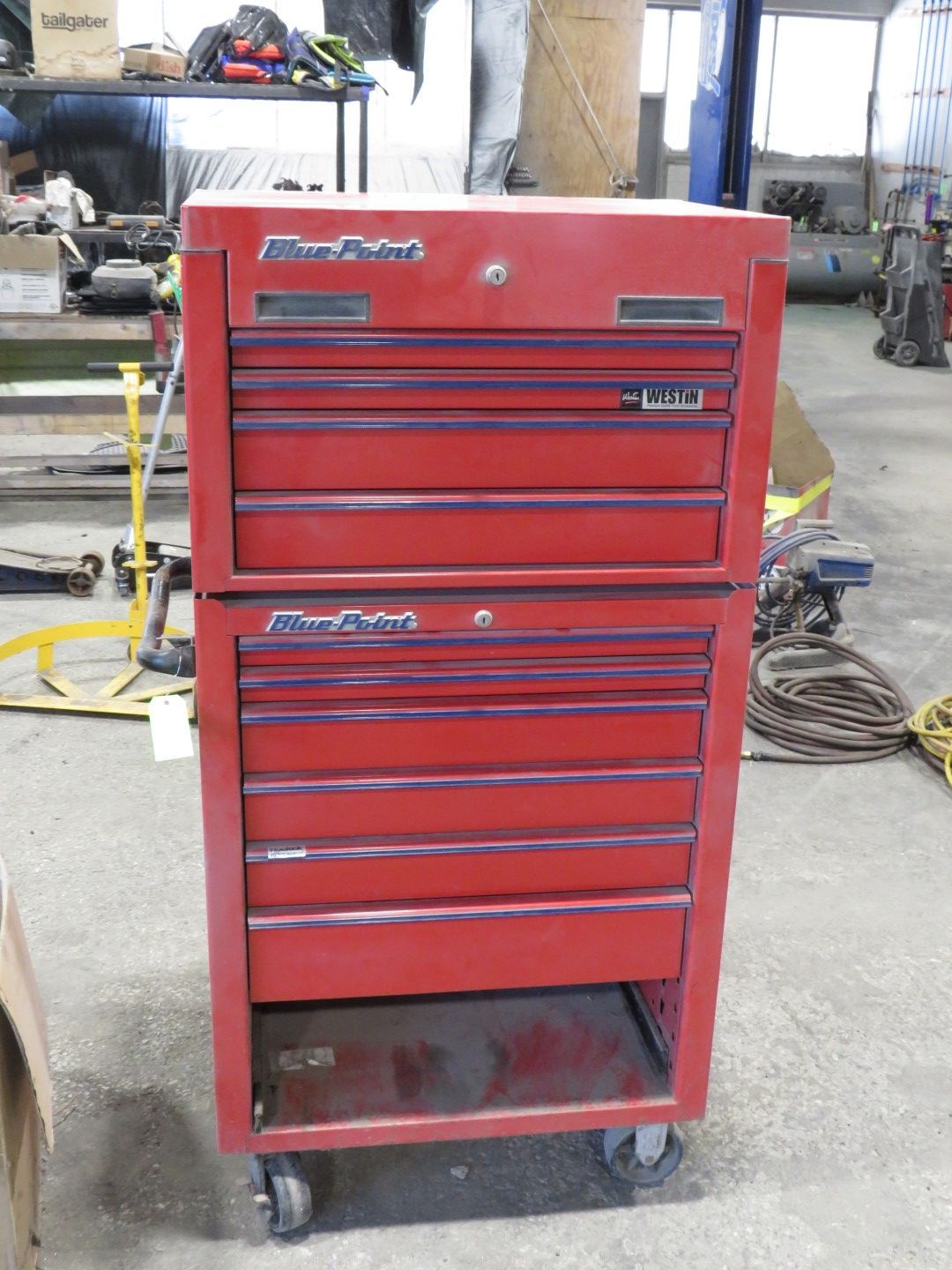 Red, two-piece tool chest on wheels, with multiple drawers, in a workshop setting.