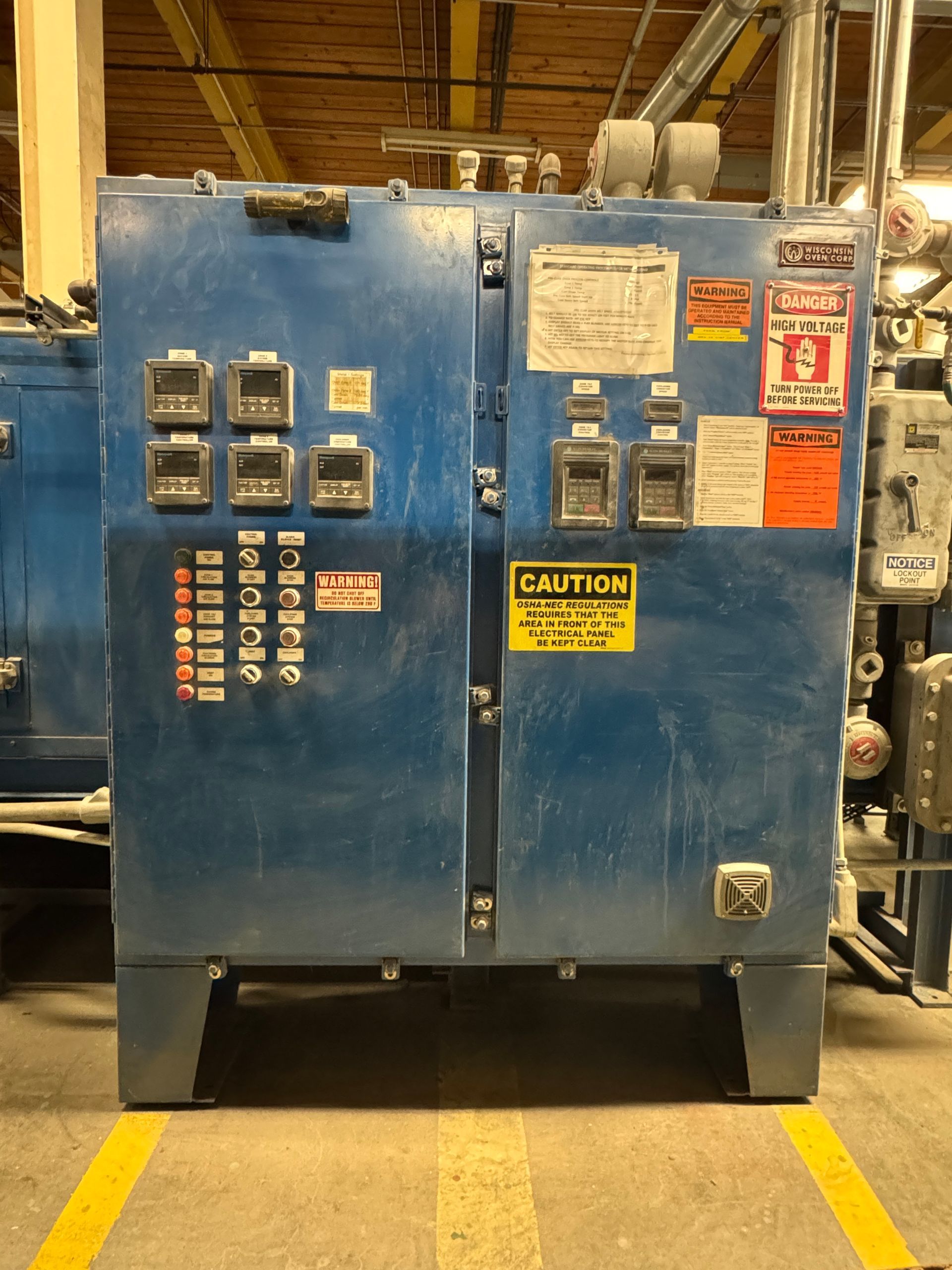 Blue industrial control panel with gauges and warning labels.