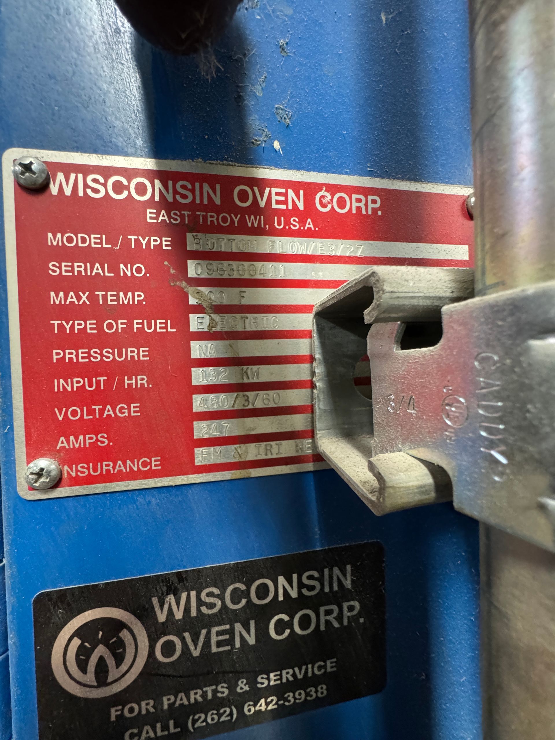 A red and white Wisconsin Oven Corp. label on a blue machine.