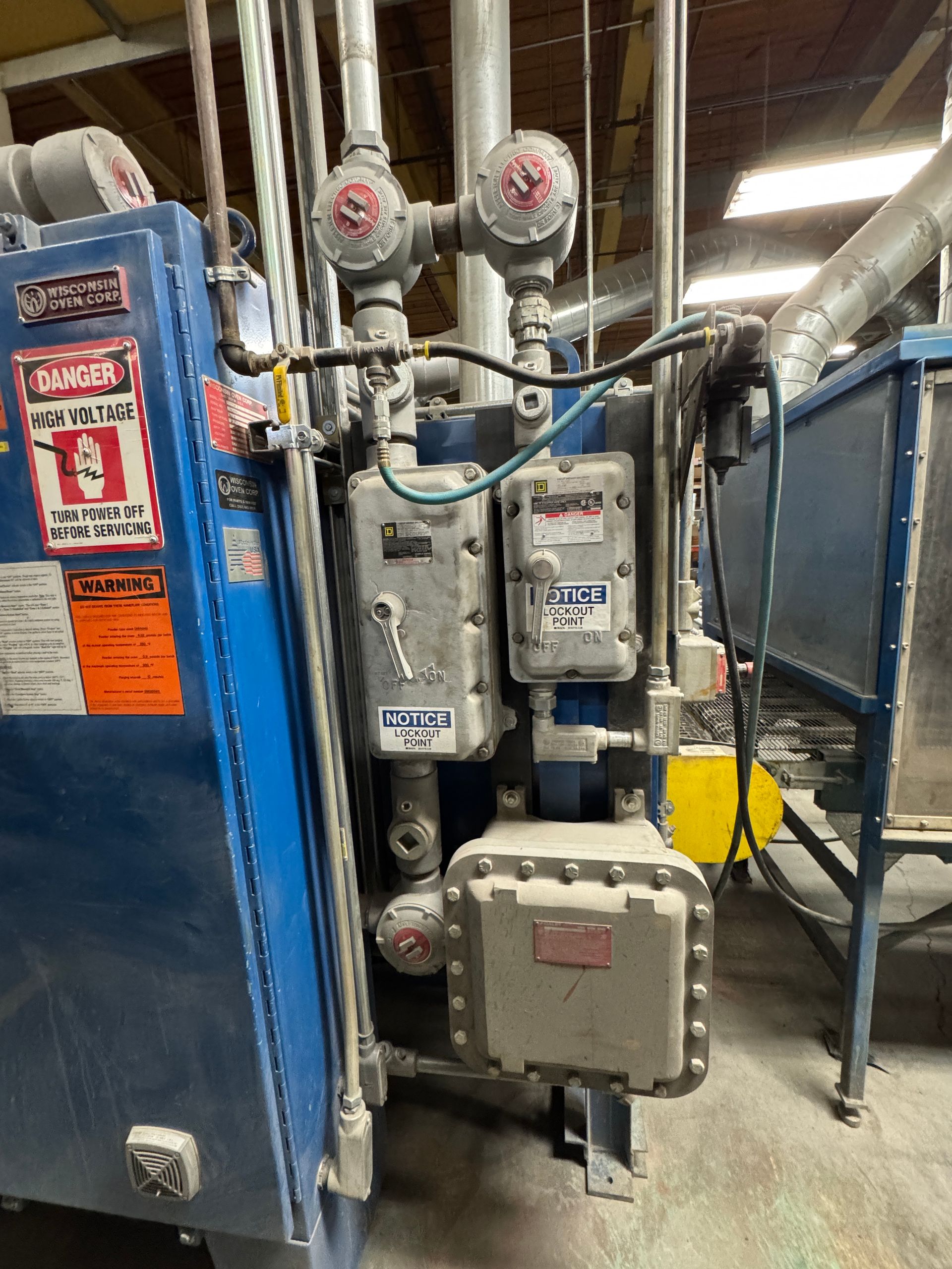 Blue machinery with various electrical boxes and piping, industrial setting.
