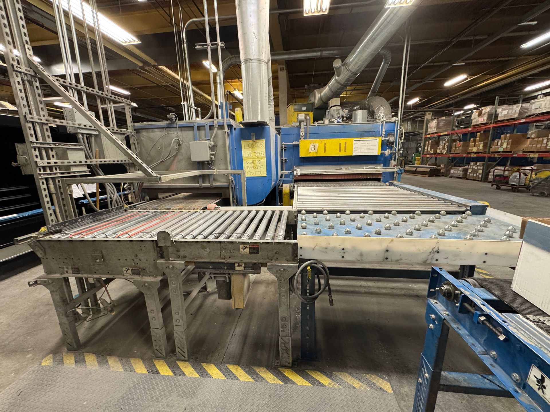 Industrial woodworking machine with rollers, in a factory setting.