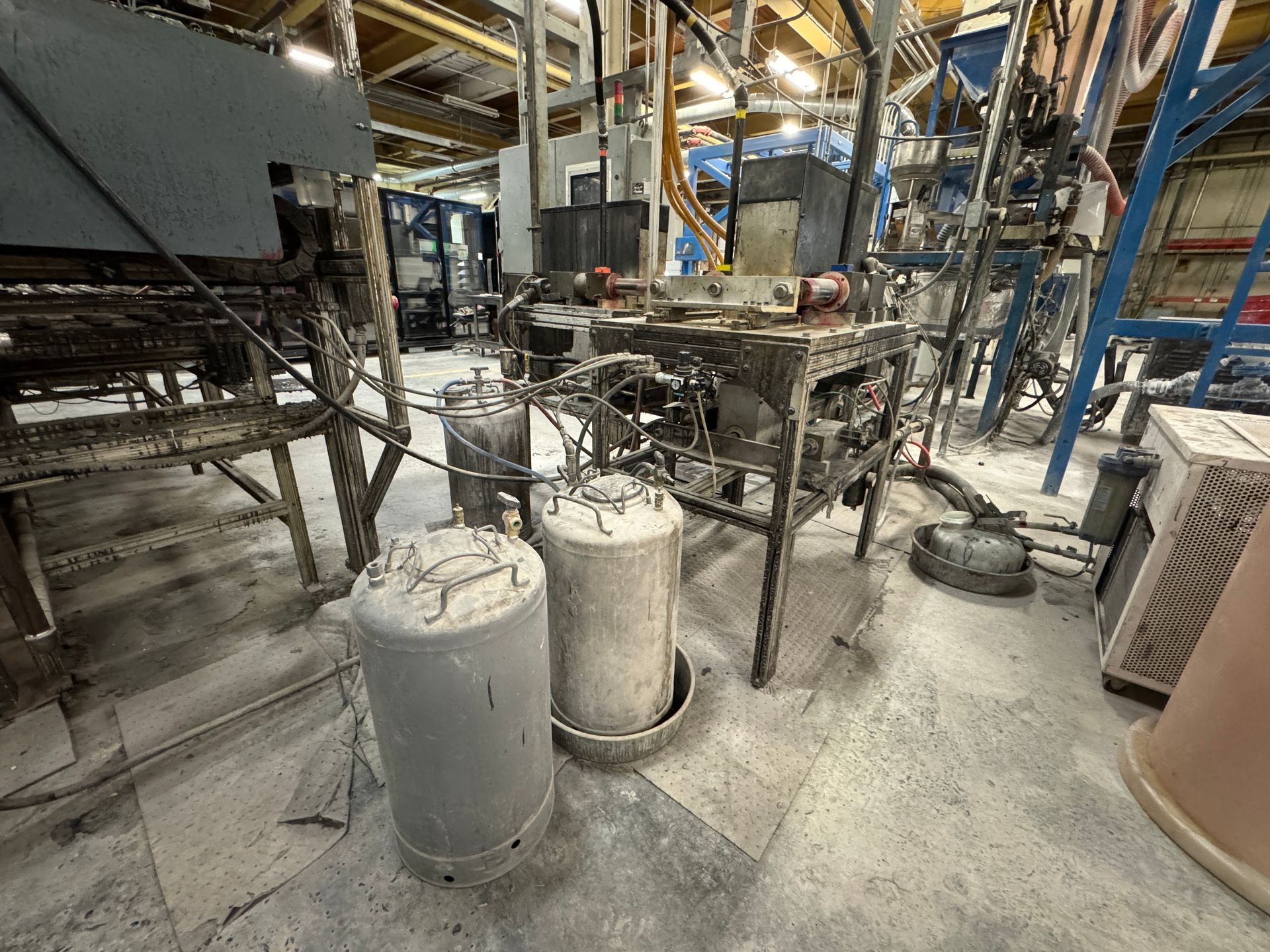Industrial setting with machinery, two cylindrical concrete forms, and equipment.