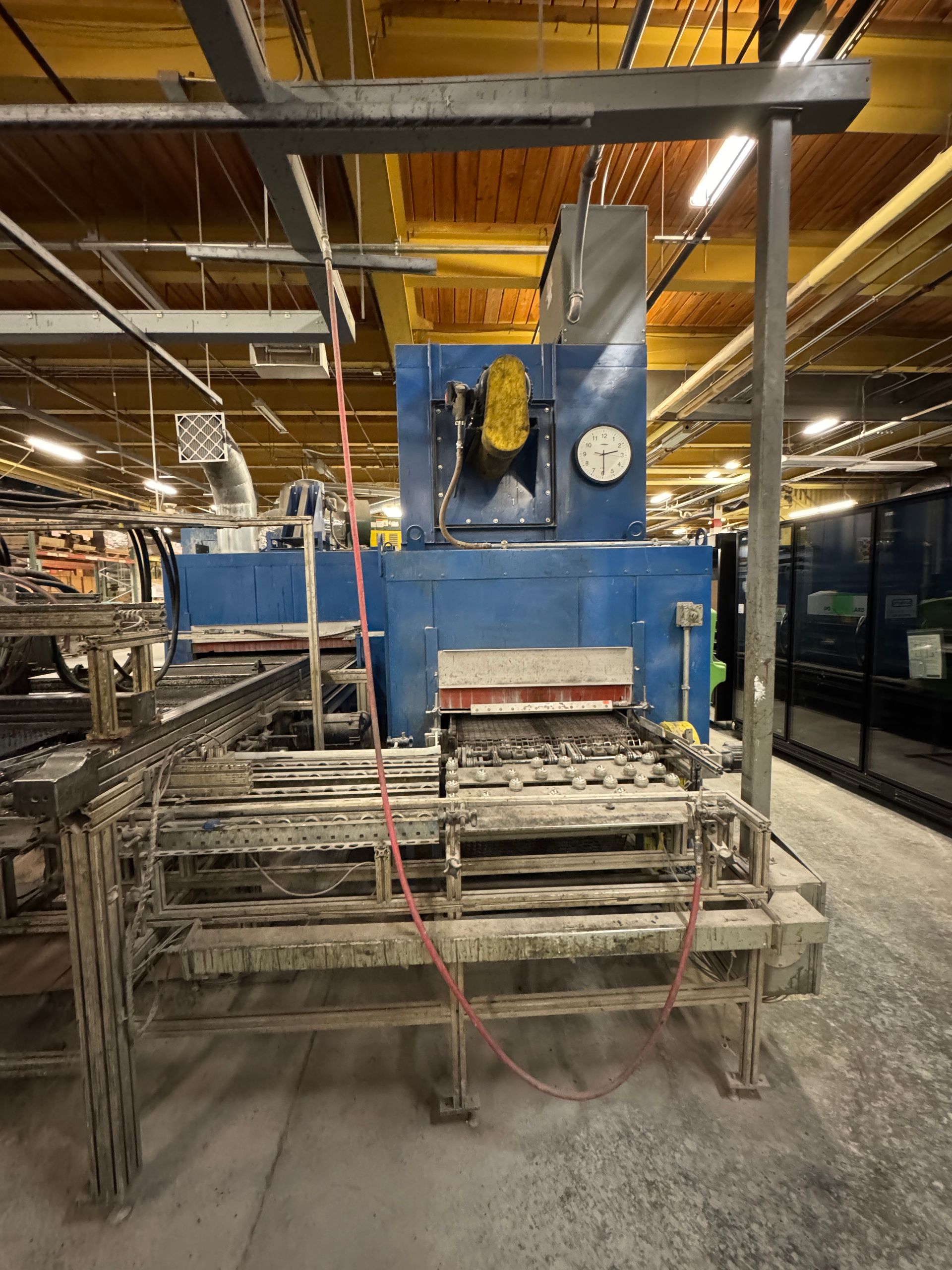 Industrial oven, blue, with a conveyor belt and gray metal frame in a factory setting.