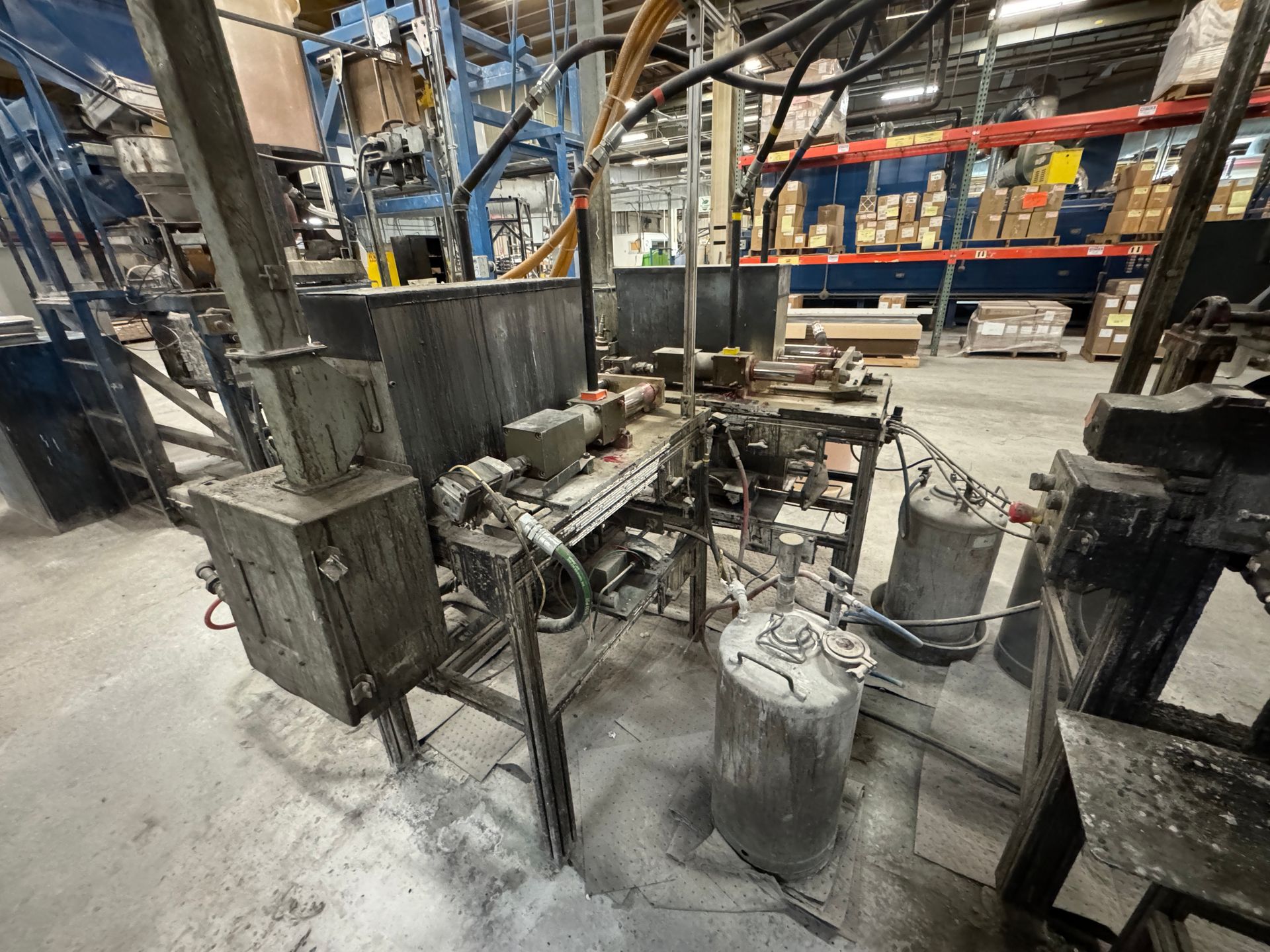 Industrial machinery in a warehouse, with pipes, tanks, and a control box.