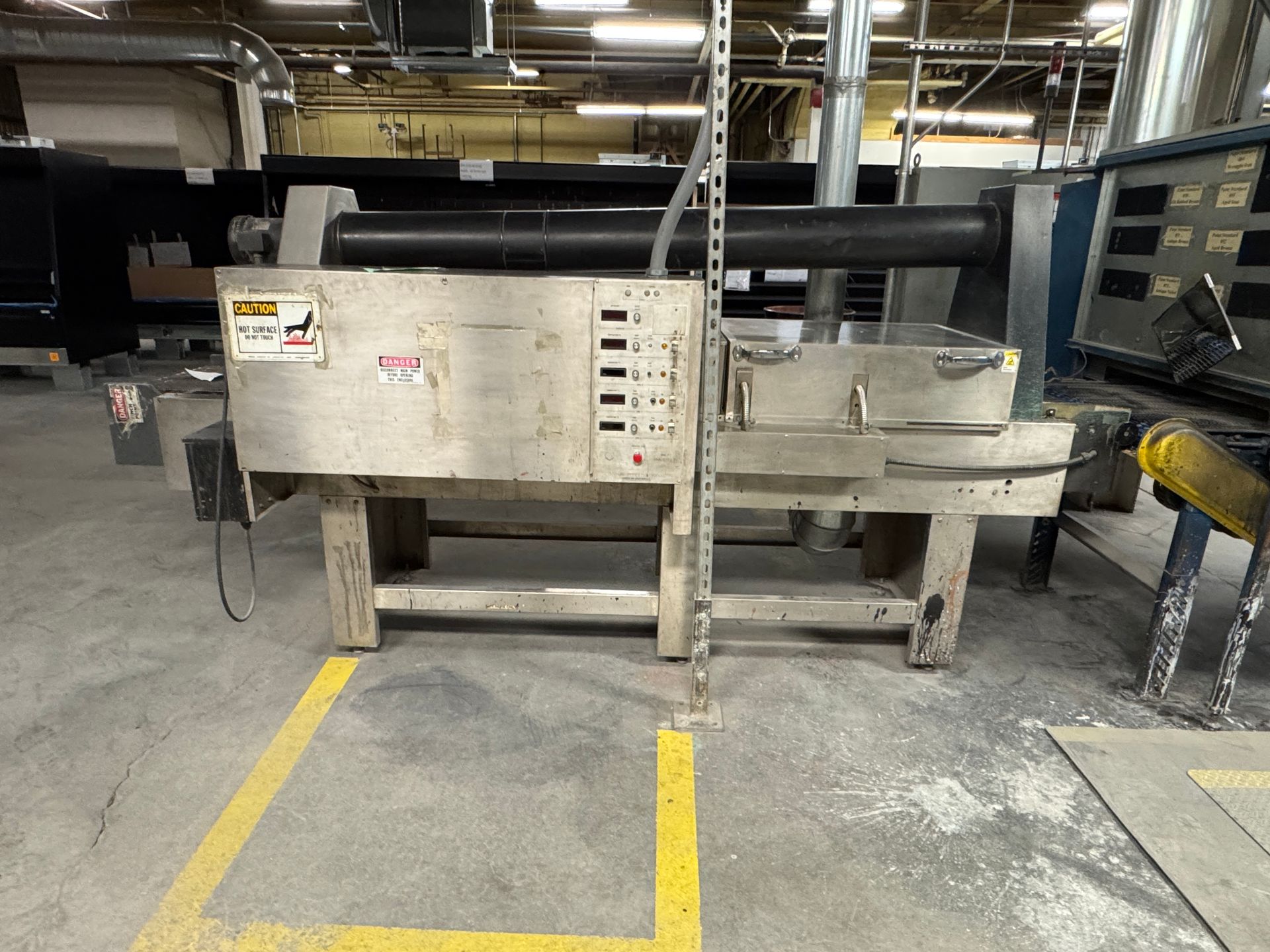 Industrial metalworking machine in a factory, with electrical controls and support structure.