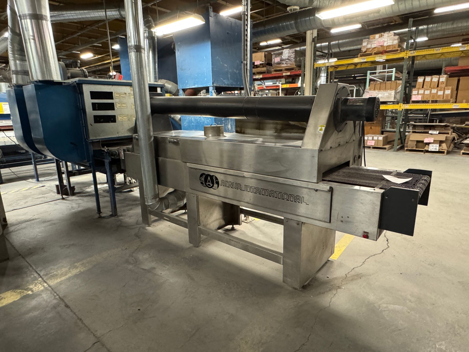 Industrial oven with stainless steel and blue components, in a warehouse setting.