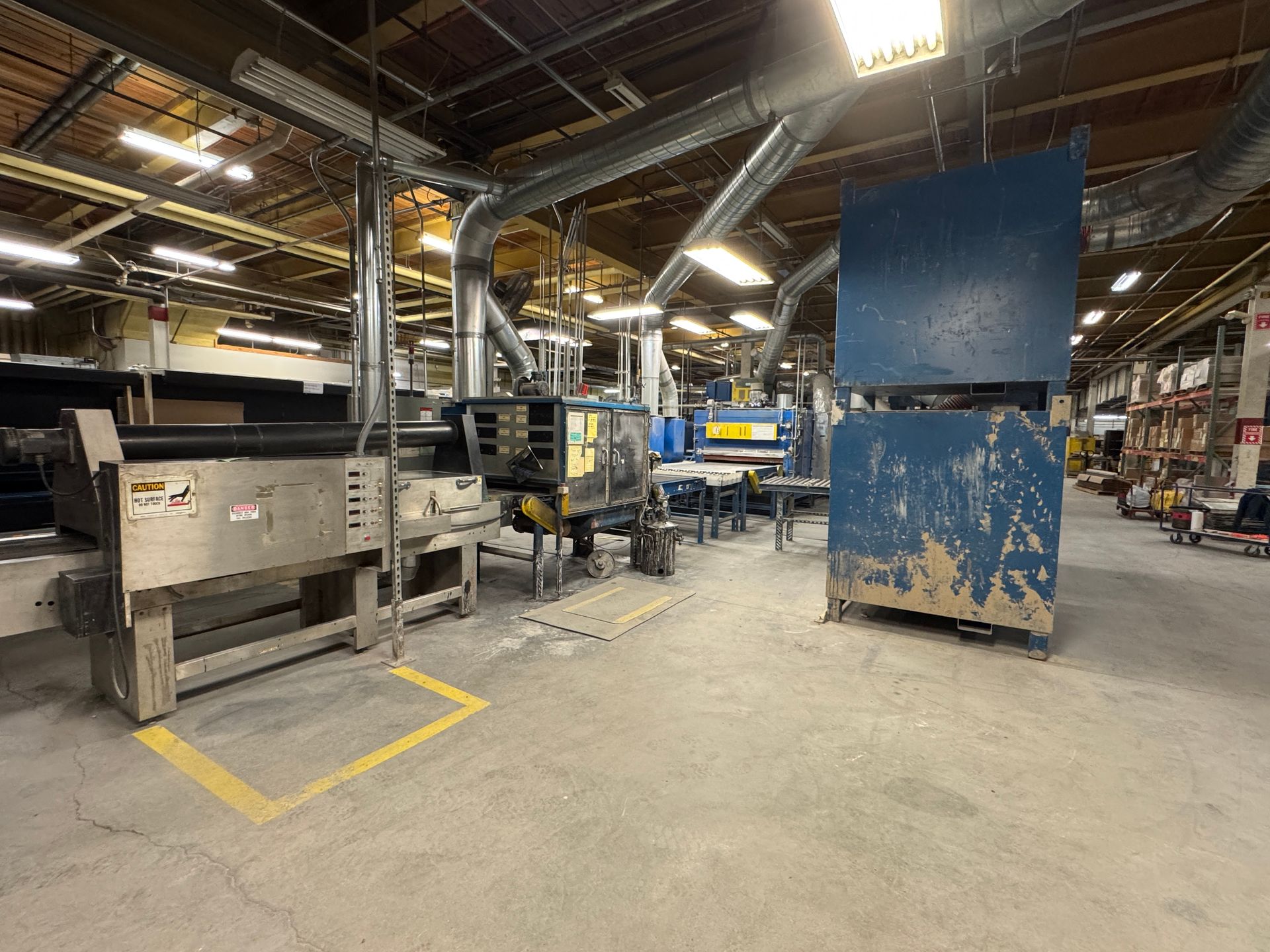 Industrial factory floor with machinery and ventilation system. Grey concrete floor, metal equipment, and blue panels.