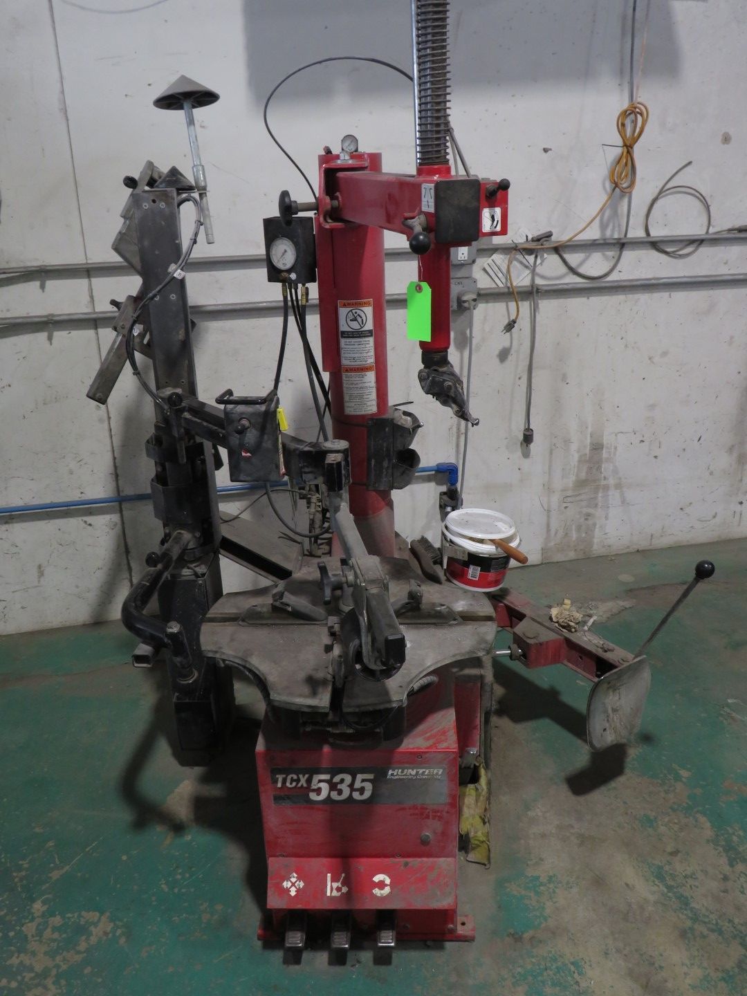 Red and black tire changer machine in a garage.