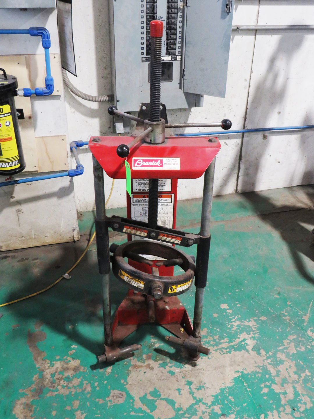 Red tire bead breaker machine in a workshop.