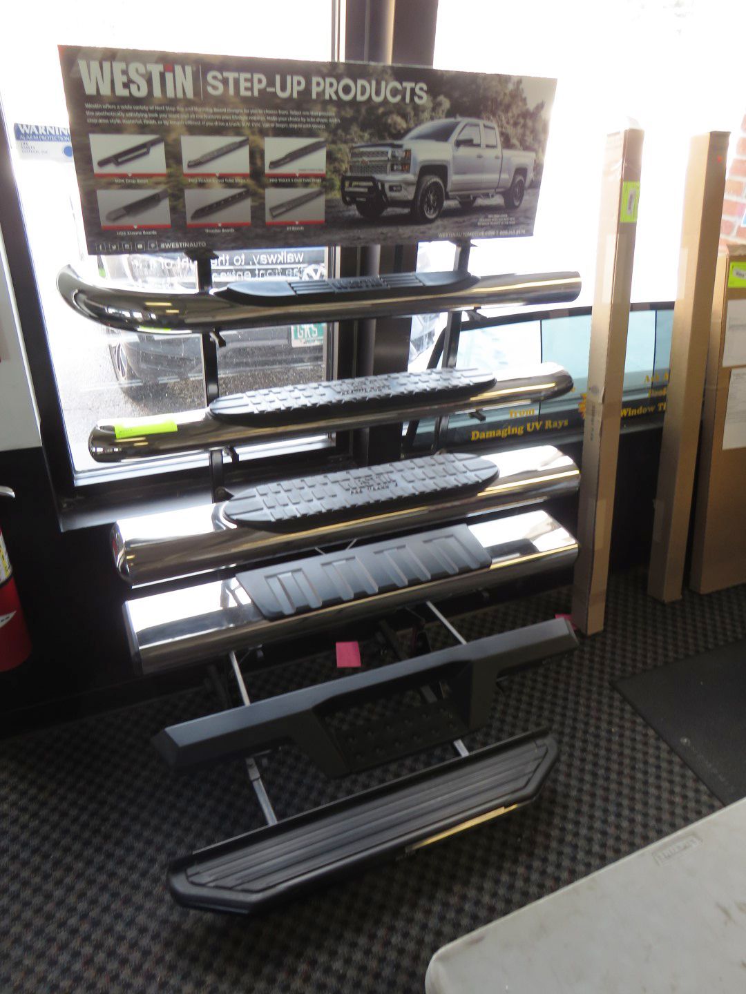 Display of Westin step-up products inside a store. Chrome and black running boards on a metal stand.
