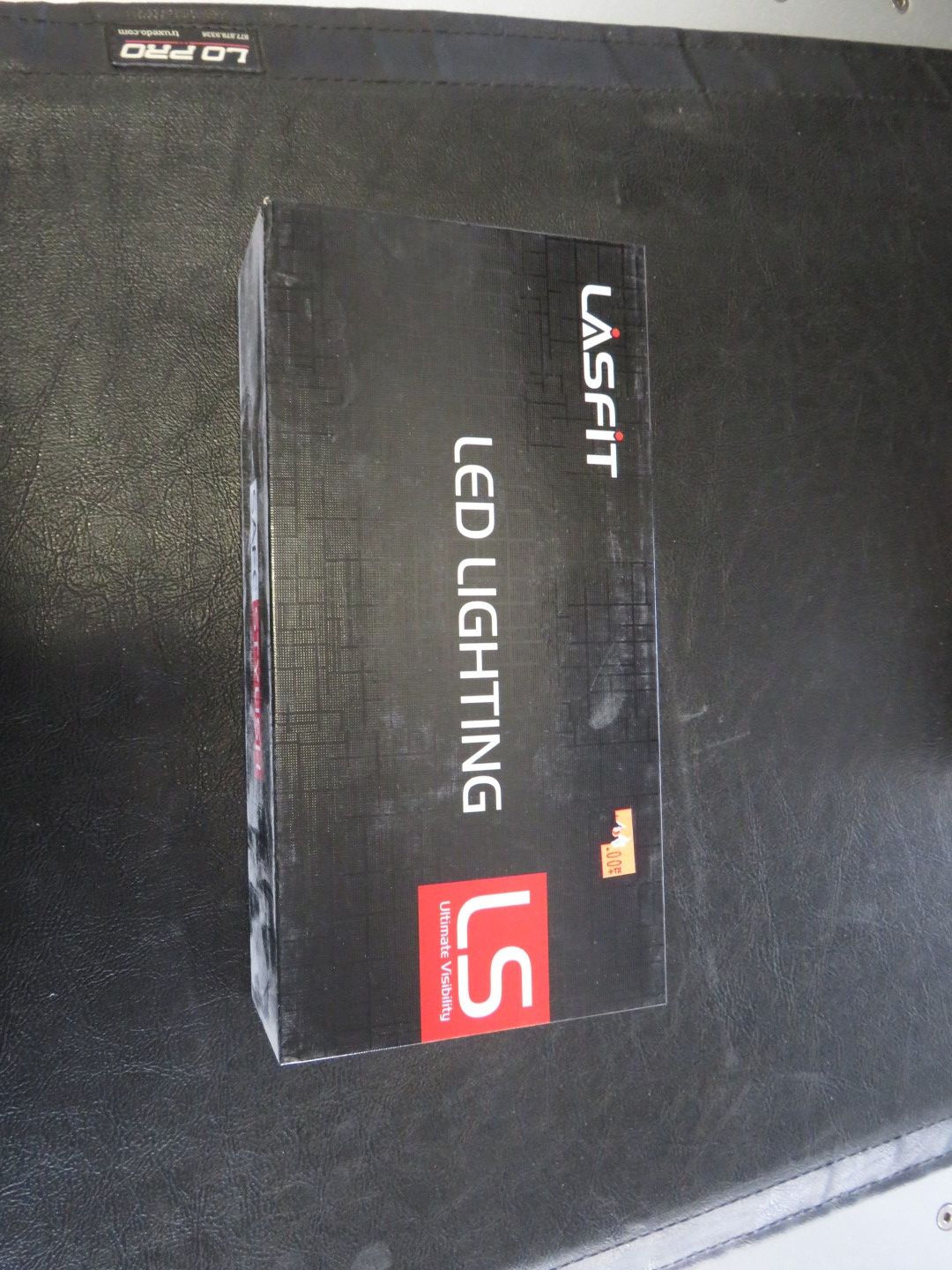 Black box of LASFIT LED LIGHTING with red and white LS logo on a black surface.