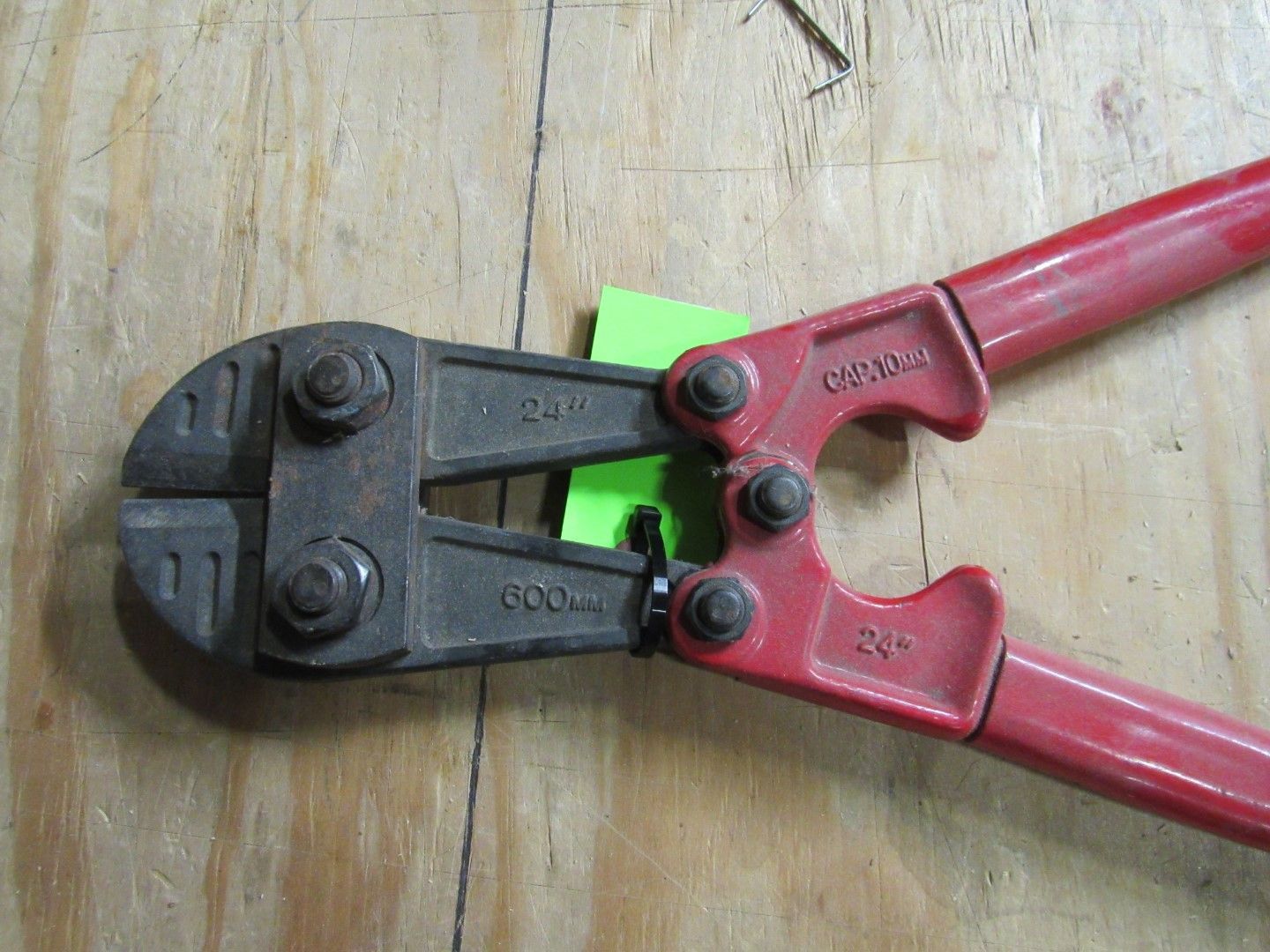 Red bolt cutters on wooden surface.