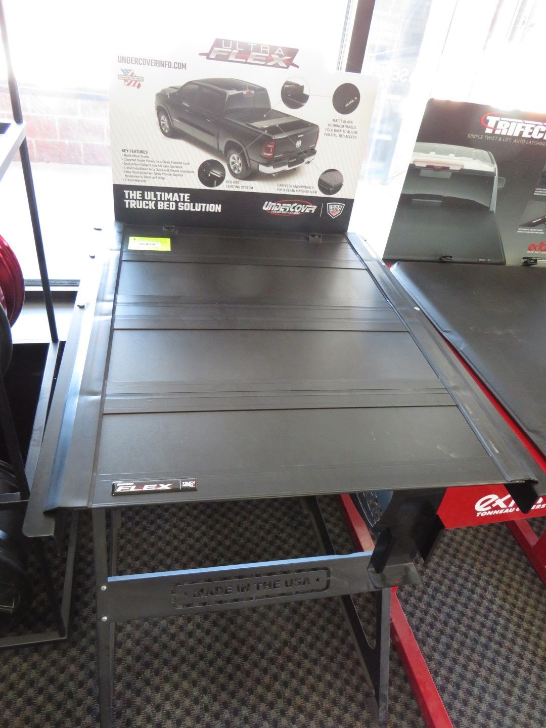 Black truck bed cover on display, with product information and a truck graphic in the background.
