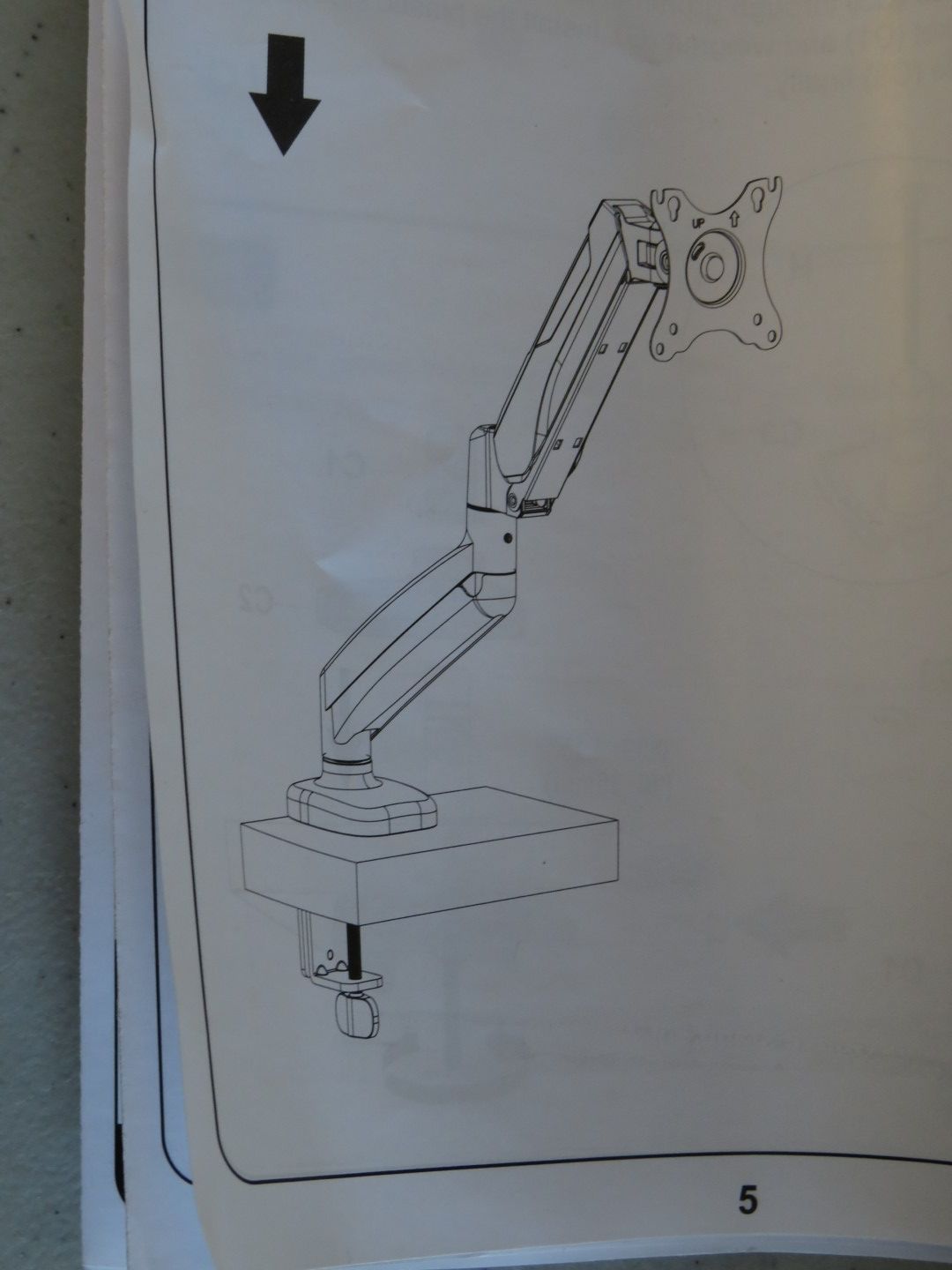 Diagram of a monitor arm clamped to a desk, with the arm extended, and pointing toward an arrow above.