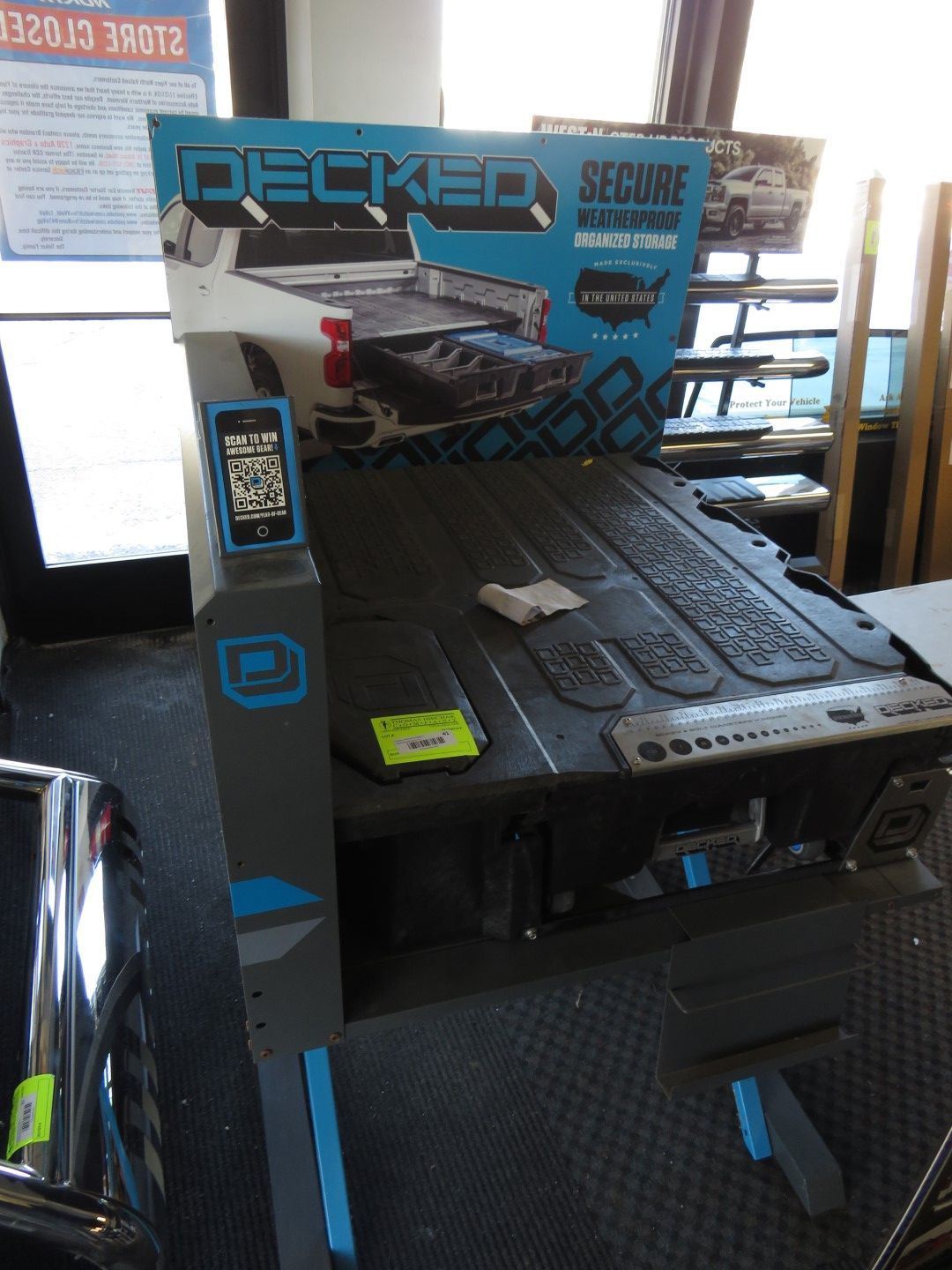 Decked truck bed storage system display, blue and gray, in a retail setting.