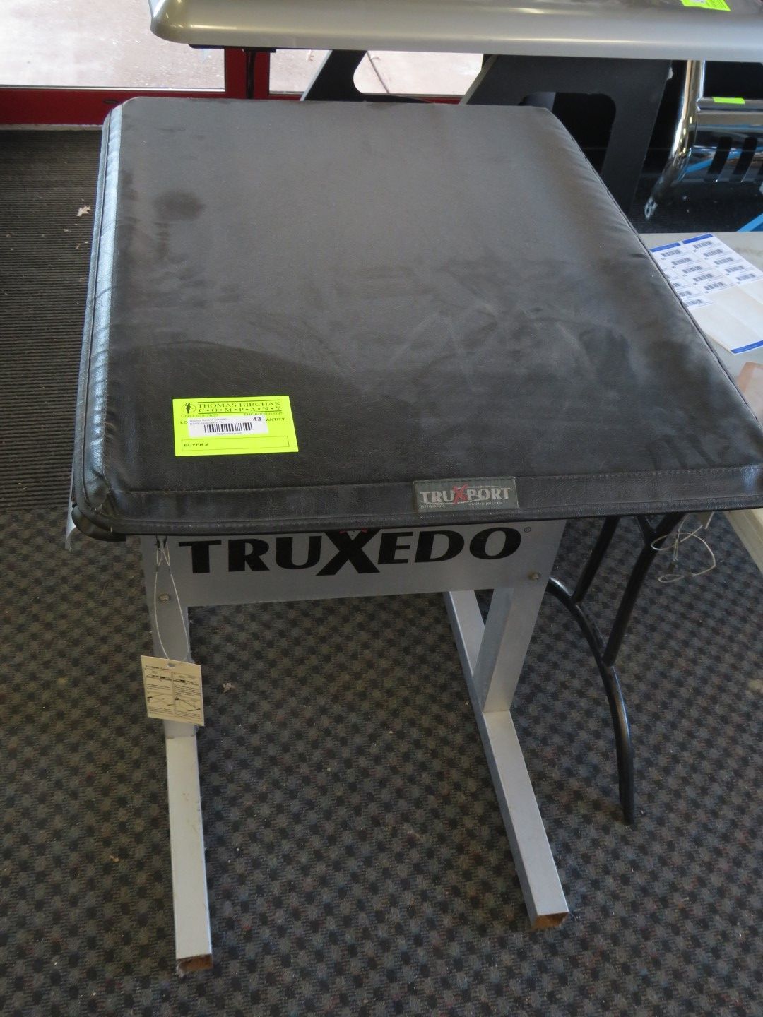 Black TruXedo truck bed cover on a metal table, indoors.