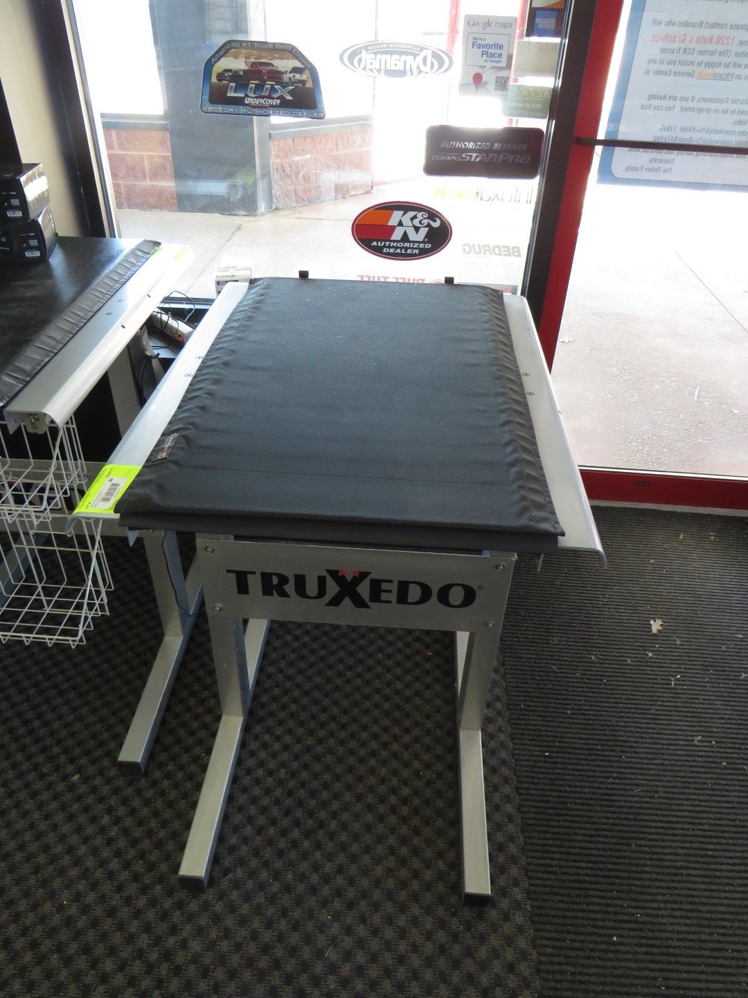 A TruXedo display table with a black bed cover, silver frame, in a store setting.