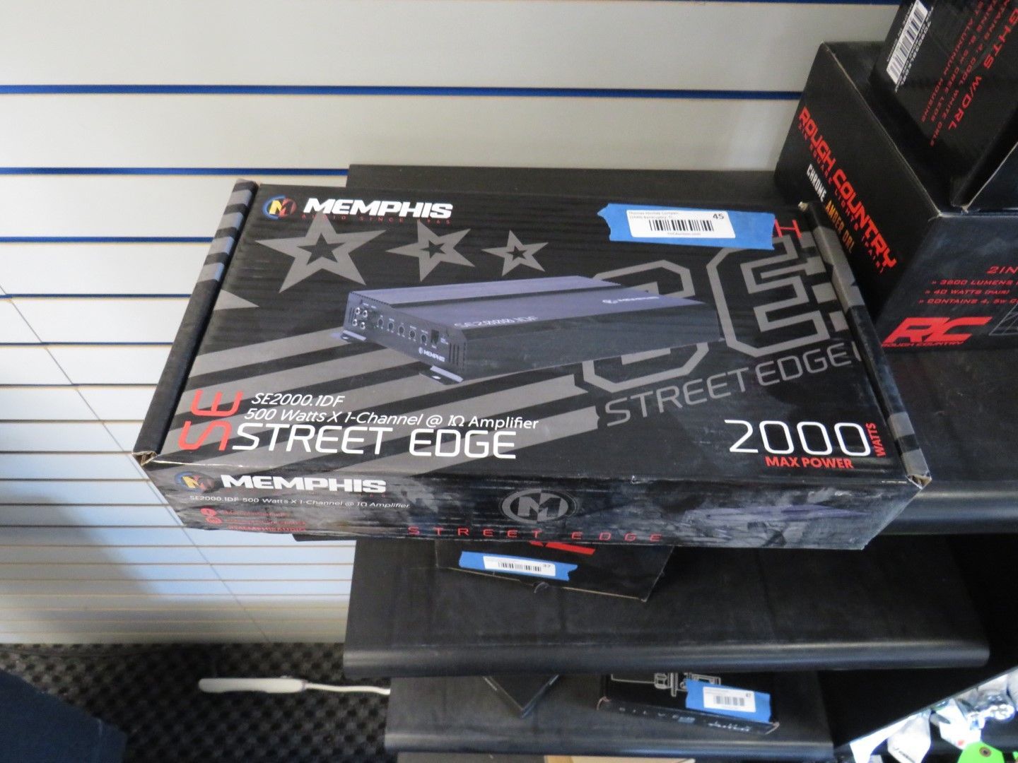 Box for a Memphis Street Edge car amplifier, black with blue accents, on a shelf.