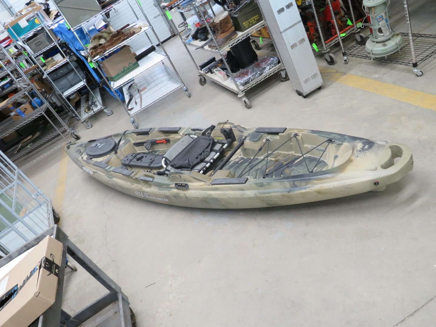 A camouflage-patterned kayak on a gray floor inside a store.