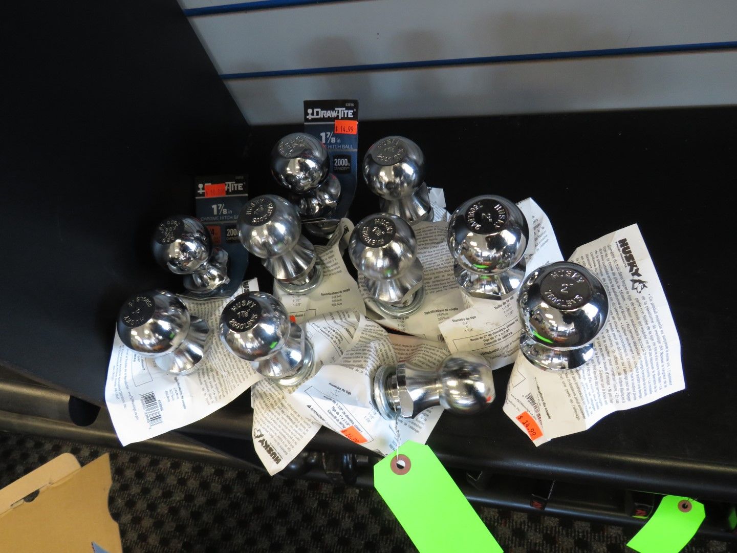 Pile of chrome hitch balls on newspaper, with boxes and a green tag, on a black surface.
