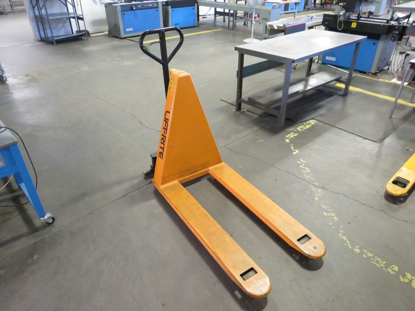 Orange and yellow pallet jack in a factory setting.