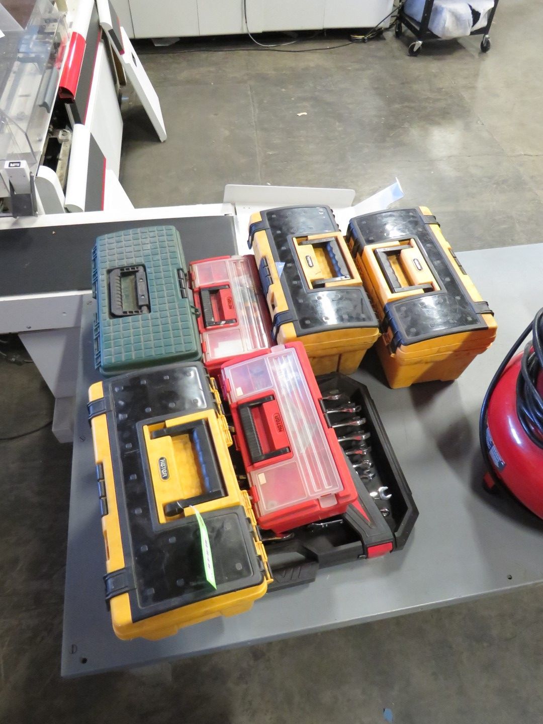 A collection of toolboxes in various colors (yellow, black, red, and green) on a gray surface.