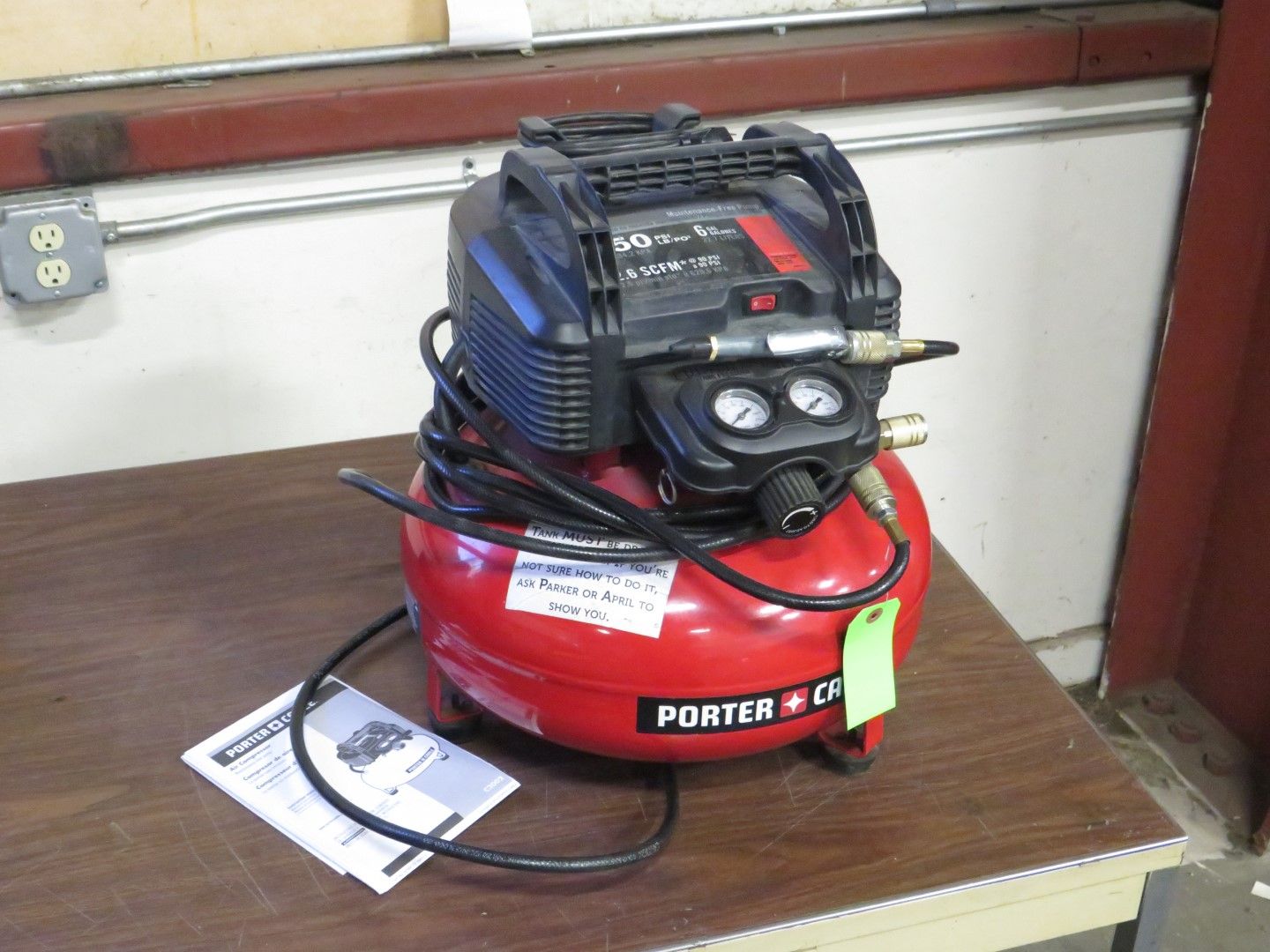 Red and black Porter-Cable air compressor on a table, with gauges and hose.