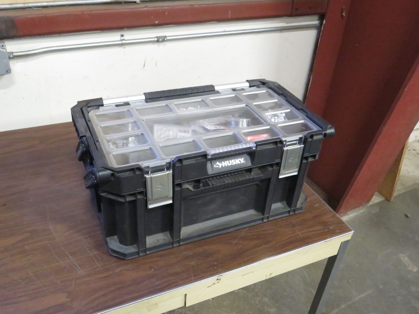 Black Husky toolbox with clear lid on a wooden table.