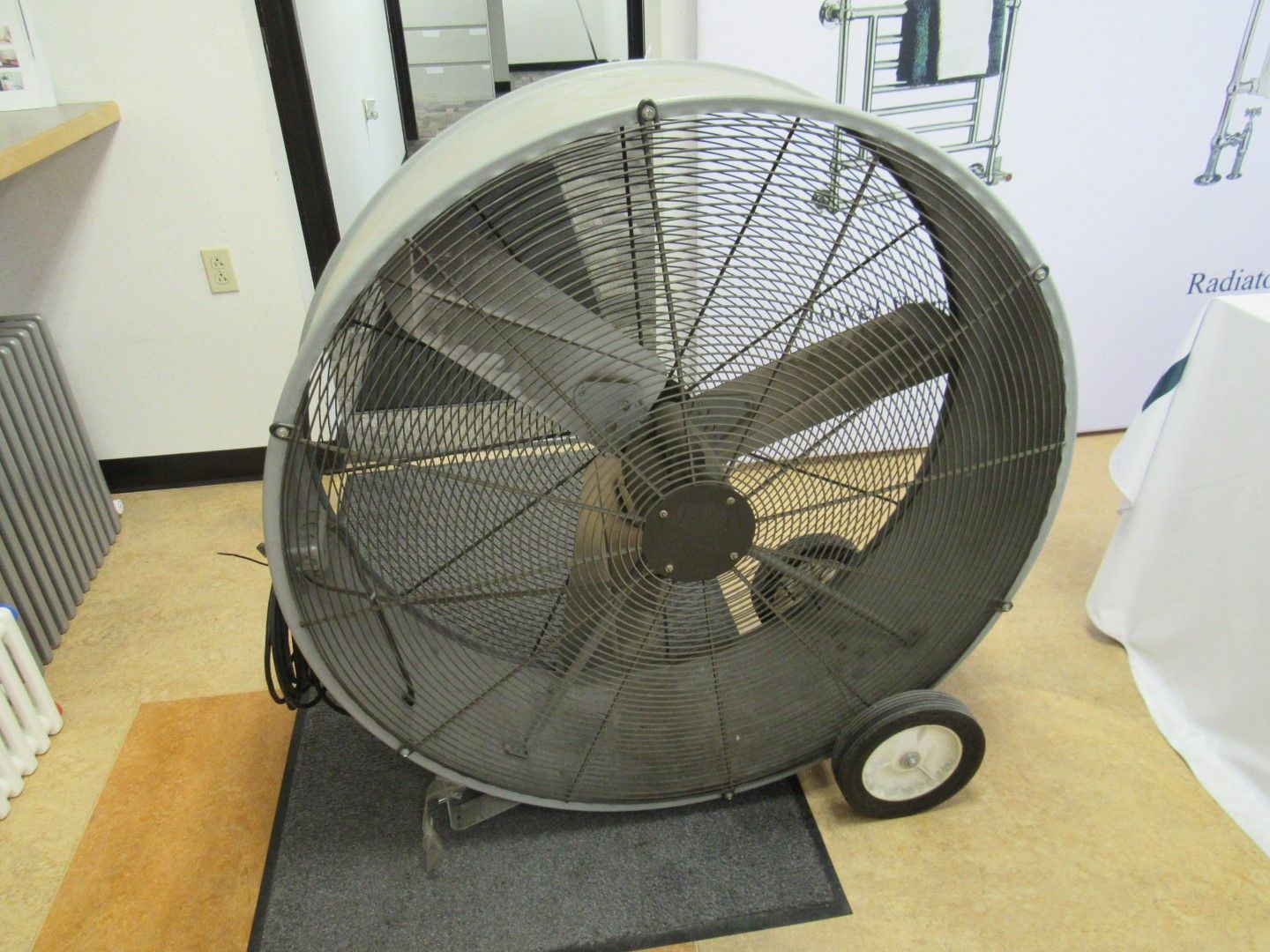 Large industrial floor fan with cage, black blades, wheels, and a protective grill.