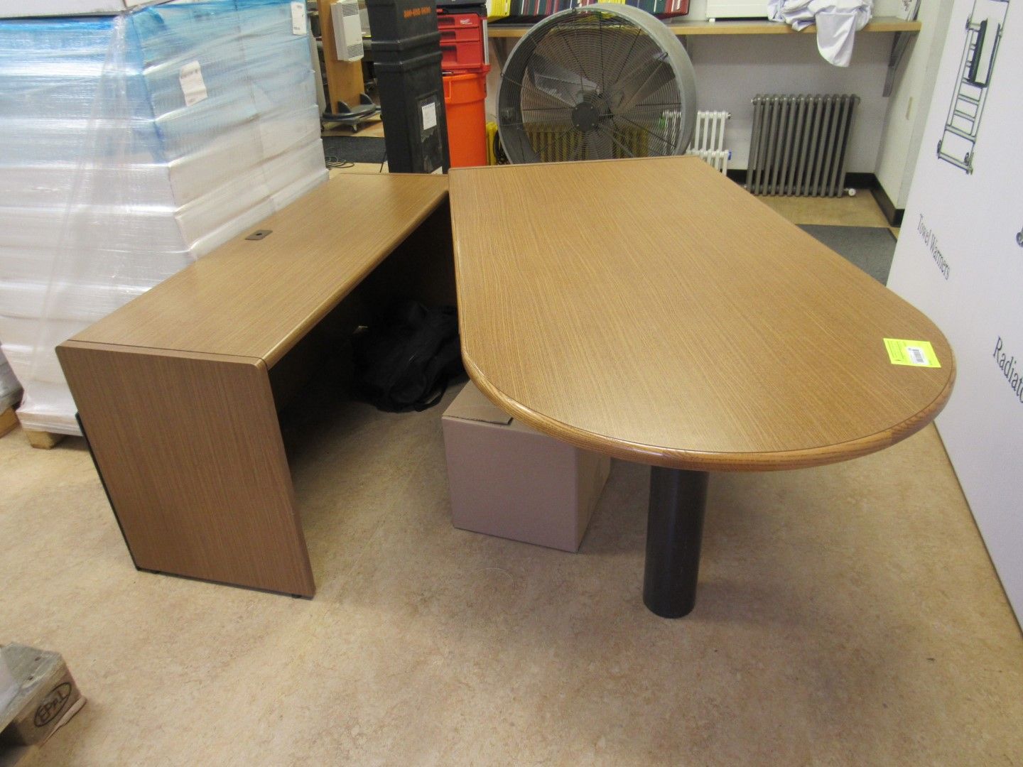 Wooden desk with an L-shaped side, a rounded end, and a black support leg.