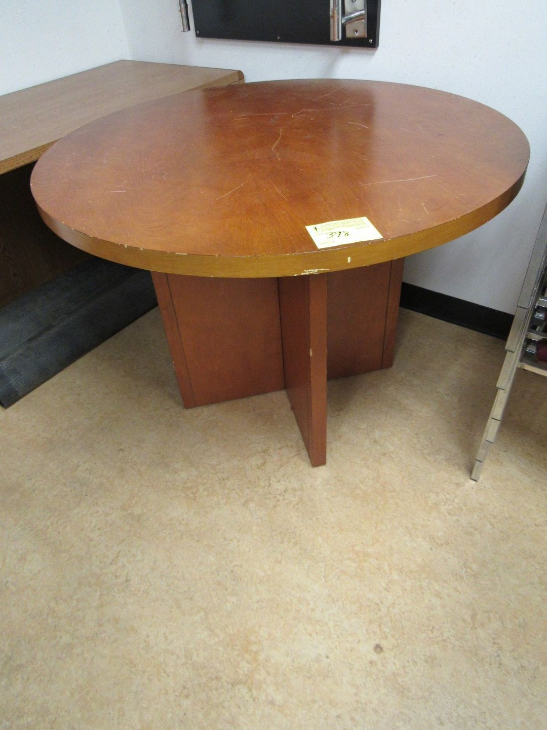 Round brown table with a pedestal base, in a room.