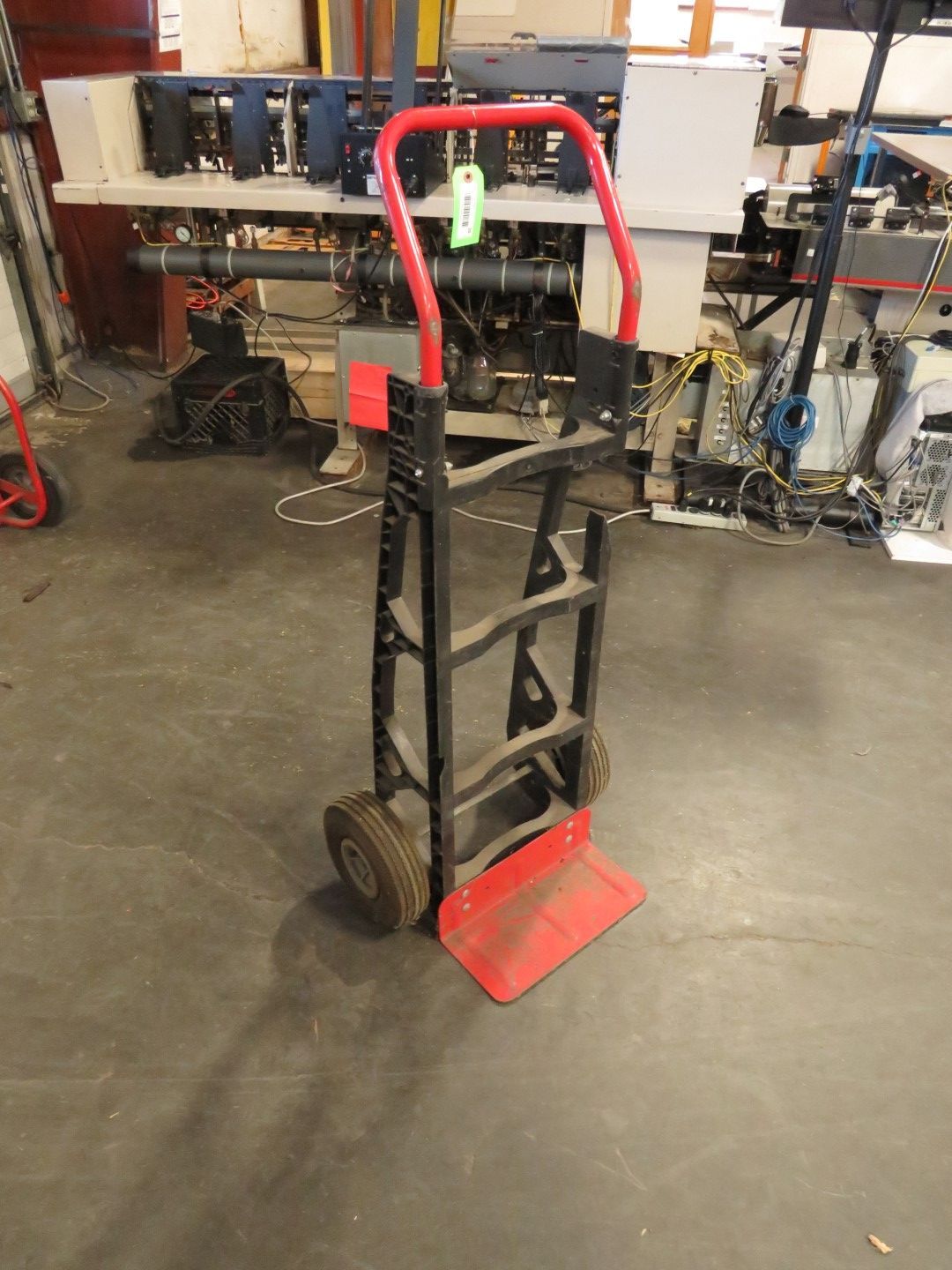 Red and black hand truck in a warehouse setting.