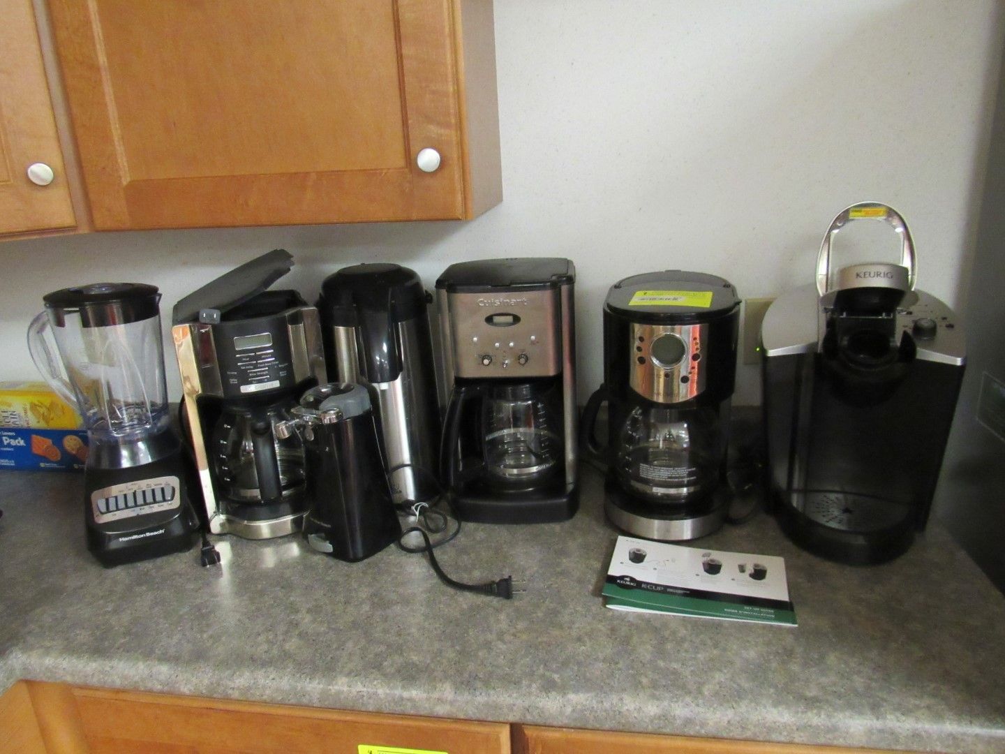Various black and silver kitchen appliances on a countertop: blender, coffee makers, and Keurig.