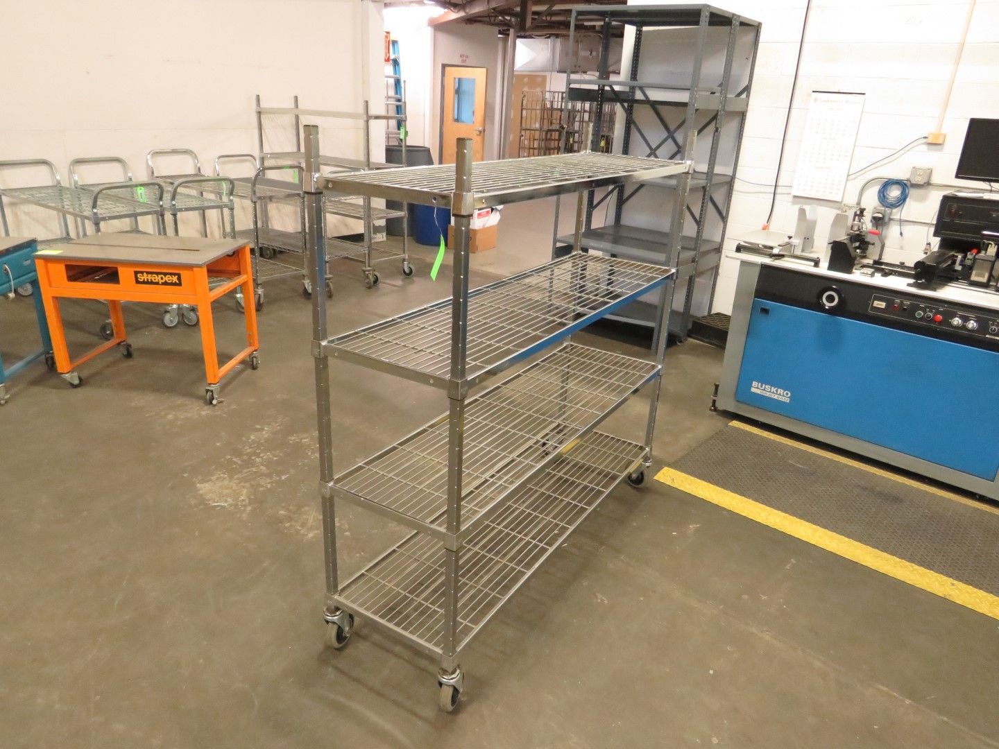Stainless steel shelving unit on wheels in a warehouse setting.