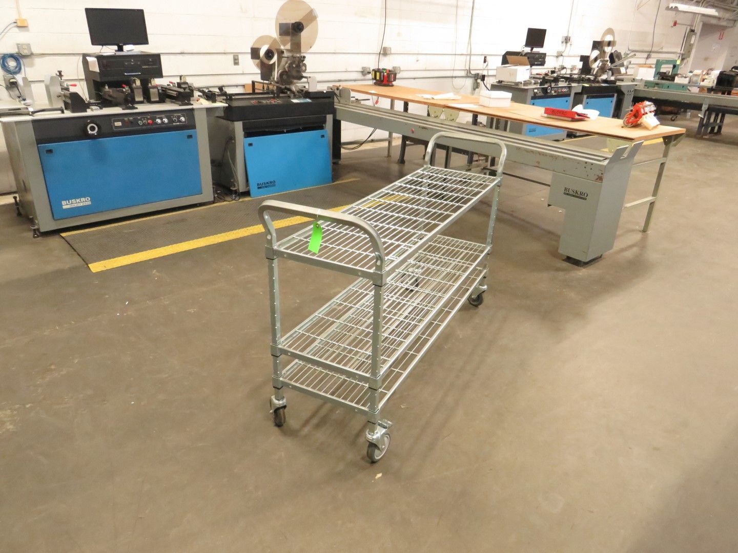 Metal shelving cart in a workshop setting with machinery.