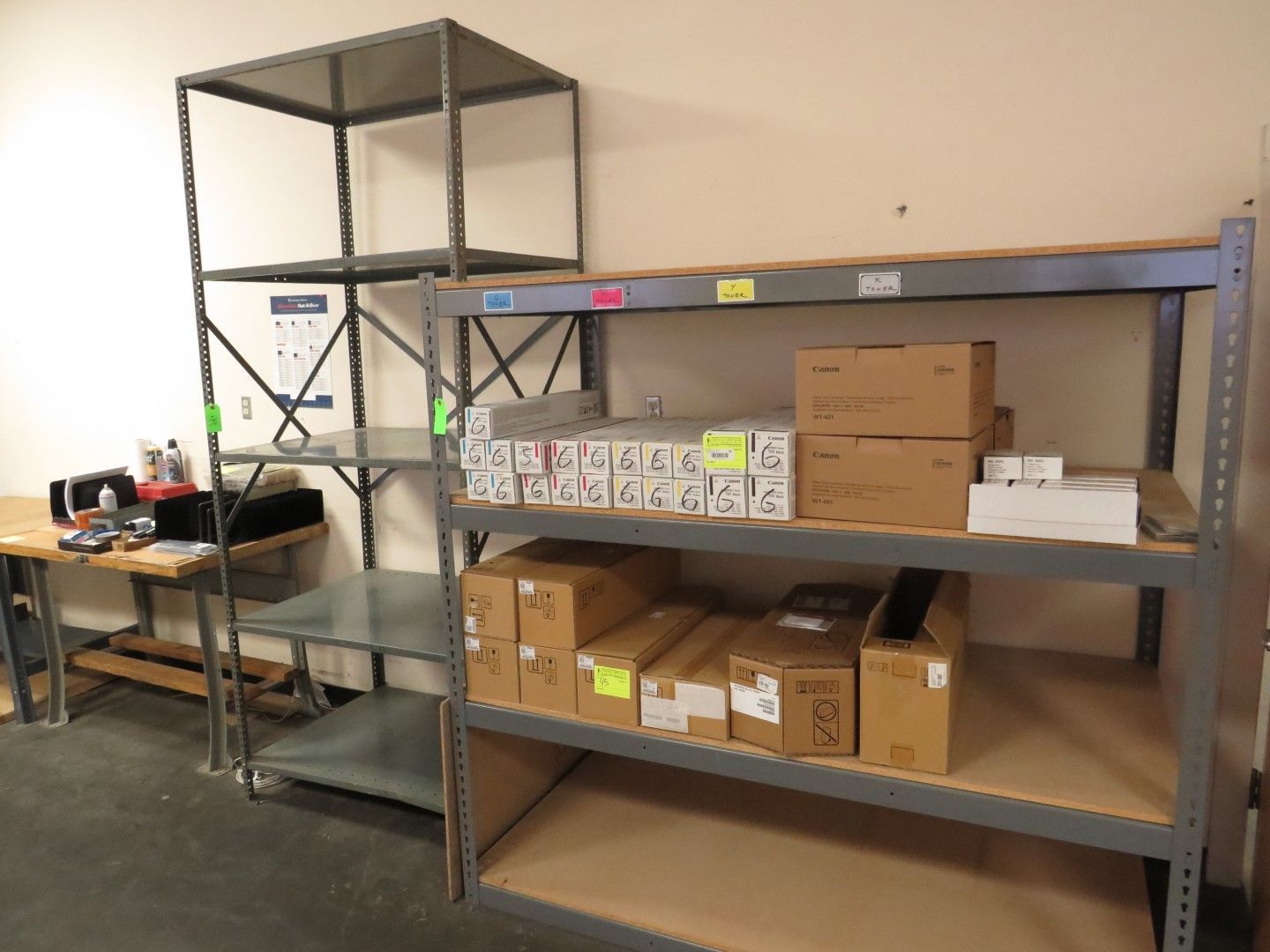 Metal shelving unit with boxes and items, next to a table with equipment.