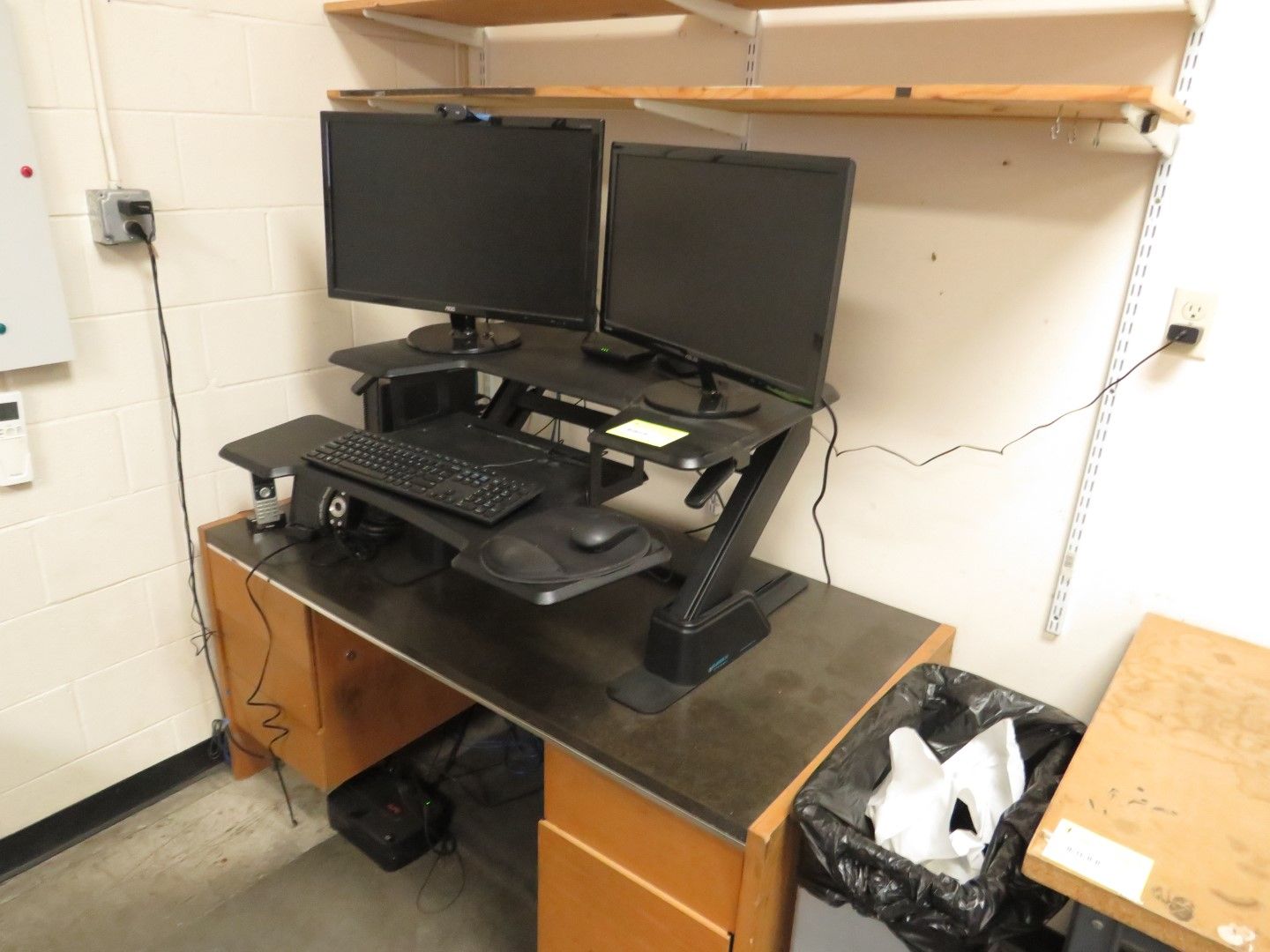 A dual-monitor workstation with a standing desk, keyboard, mouse.