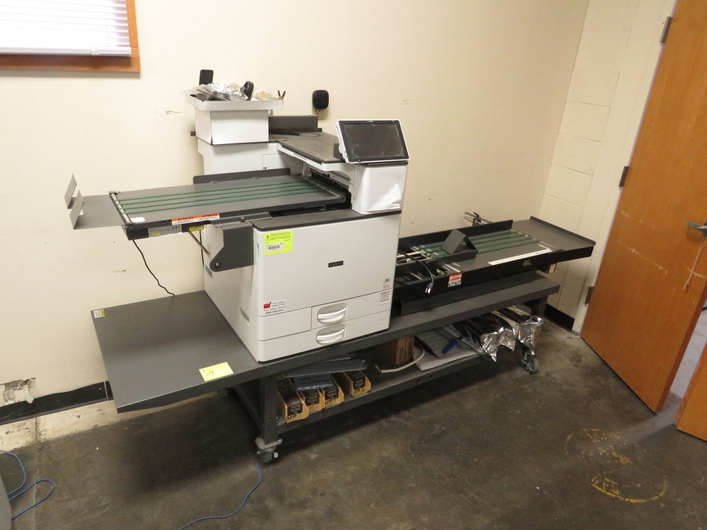 Large industrial printing machine on a rolling cart in a room.