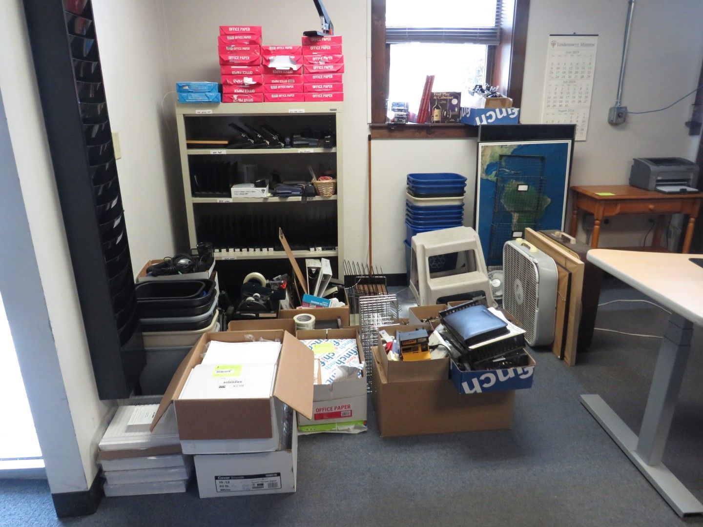 Office space with boxes, shelves, and a window.
