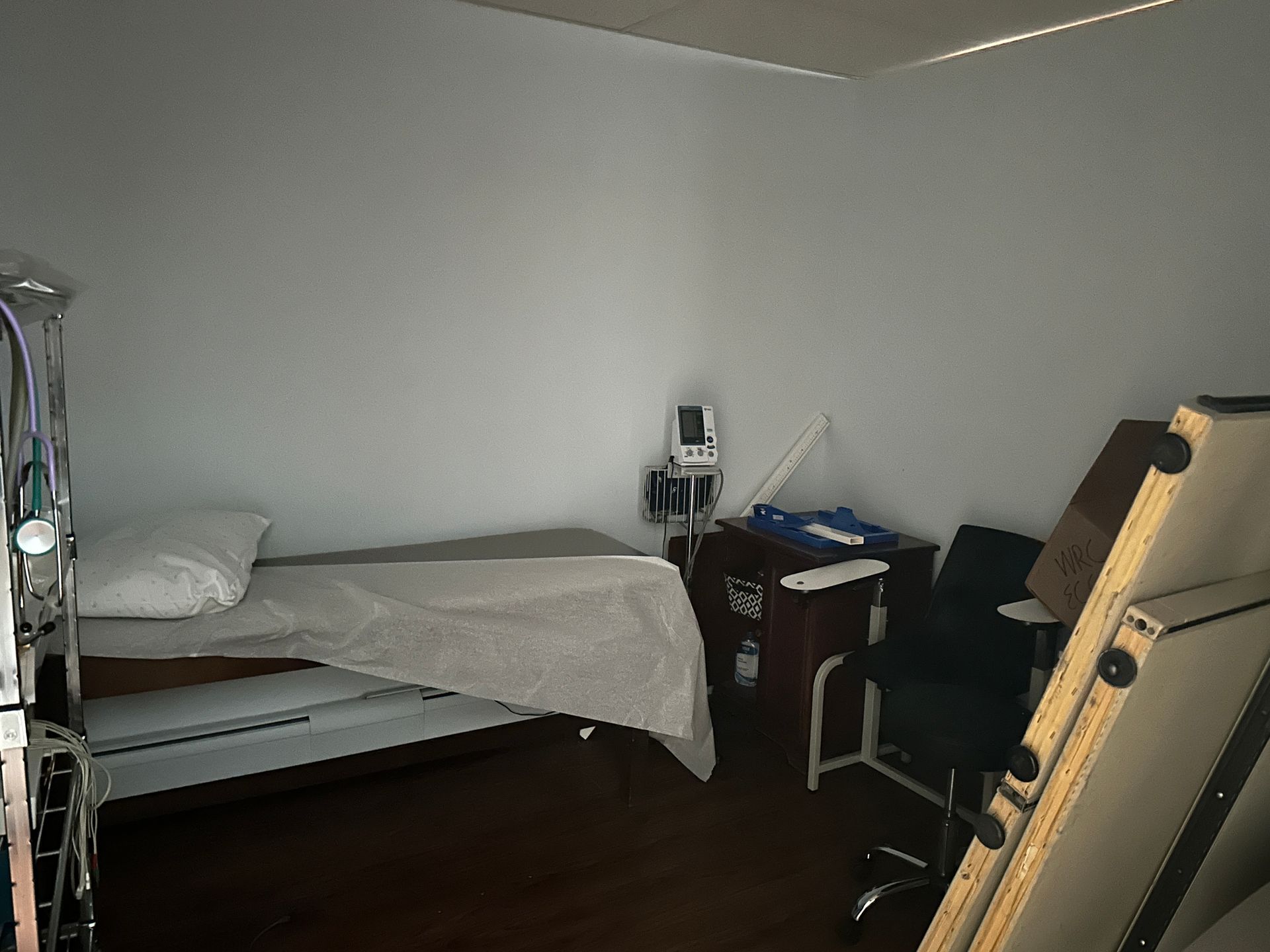 Medical examination room with exam table, equipment, and a chair.