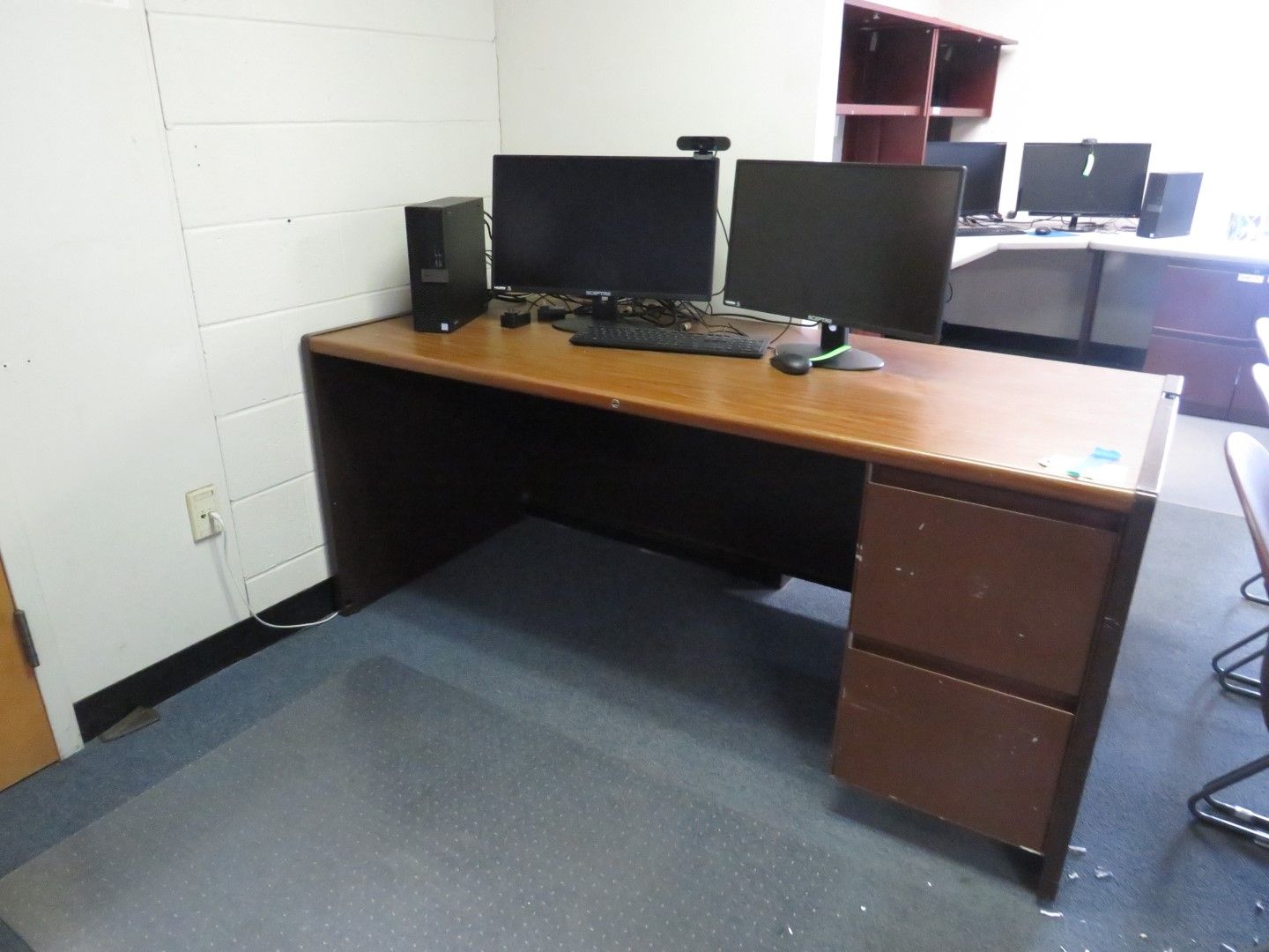 Office desk with dual monitors, computer, and file drawers.