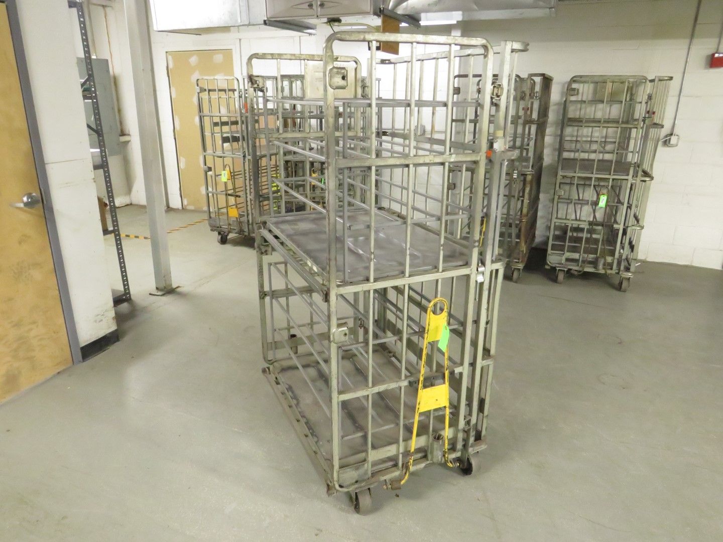 Metal rolling carts in a storage room; several stacked, industrial, on wheels.