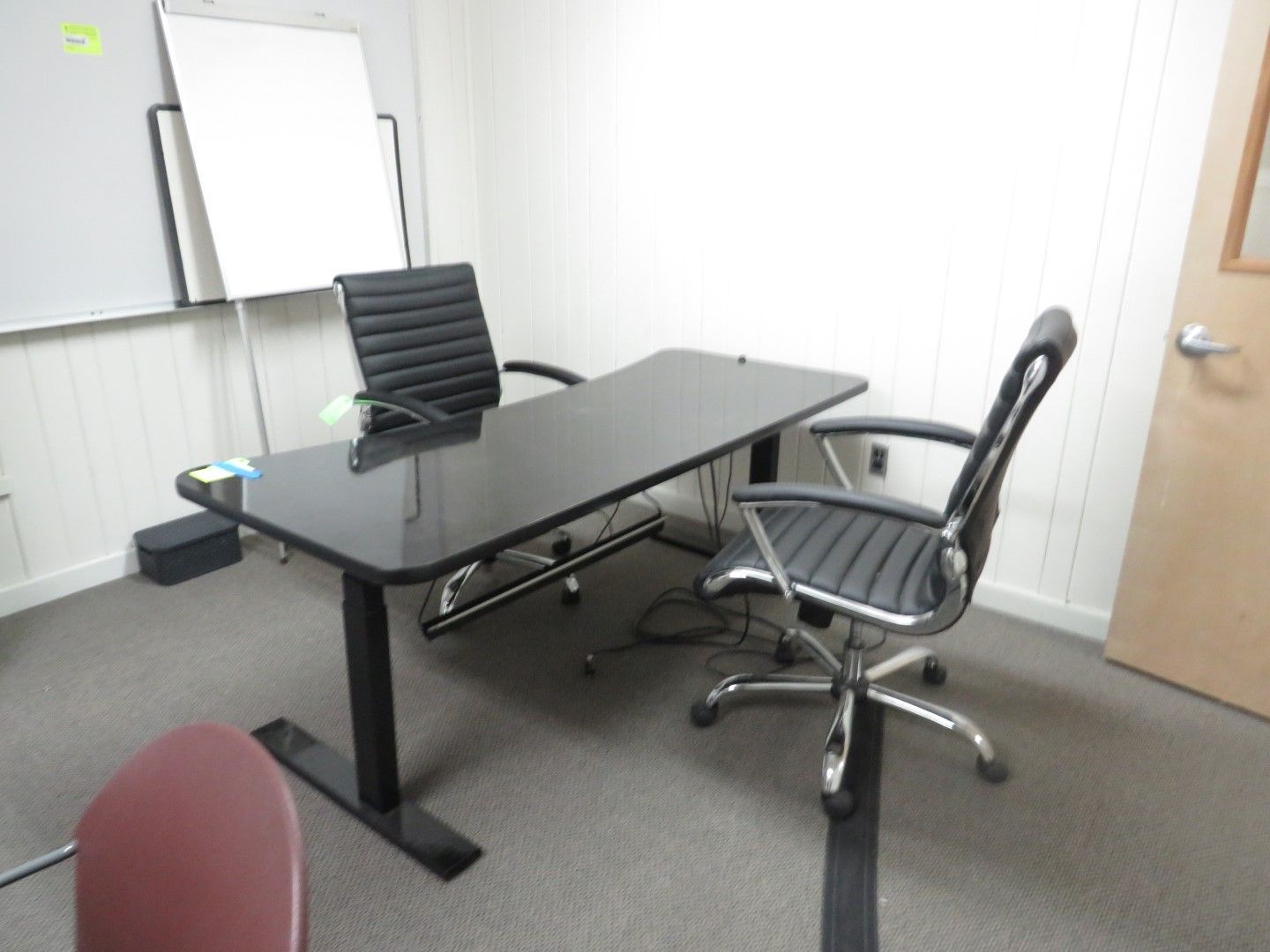 Office room with black desk, two chairs, and whiteboard.