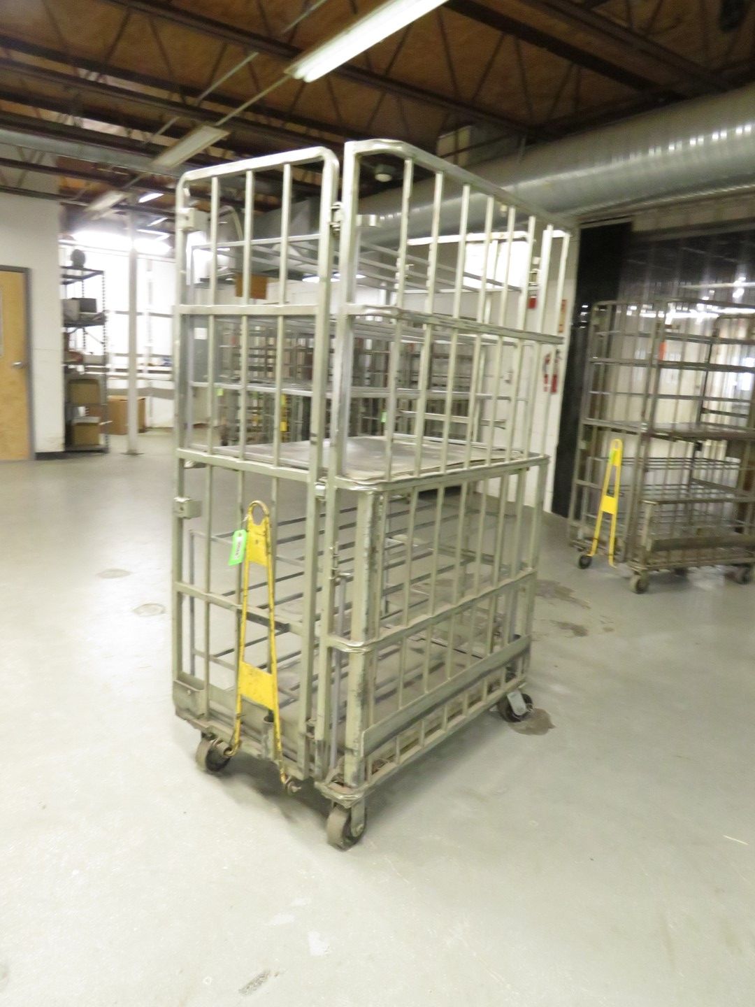 Metal rolling cart with wire cage shelves, in a warehouse setting.