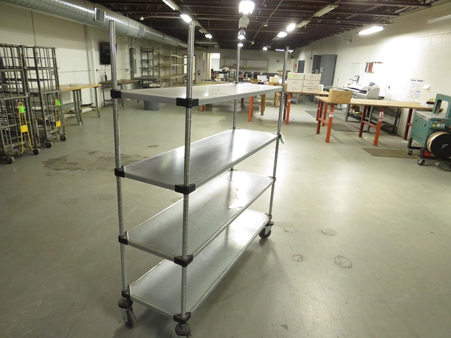 Metal shelving unit with three shelves and wheels in an industrial setting.